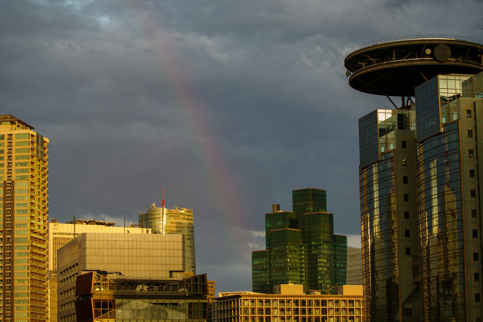Stadtansicht mit einem Regenbogen über den Gebäuden und bewölktem Himmel