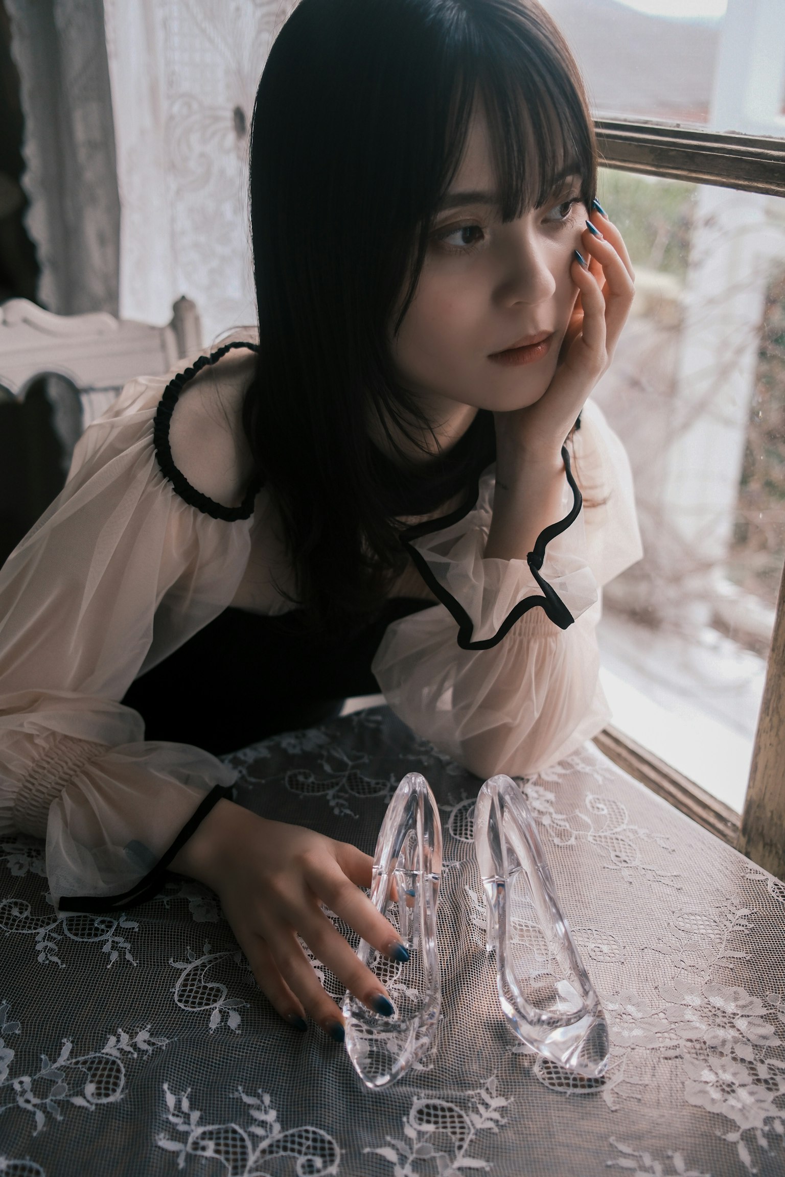 透明な靴を持つ女性が窓際で考え込んでいる