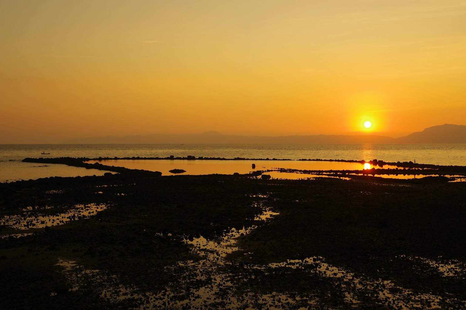Pemandangan pantai dengan matahari terbenam di cakrawala