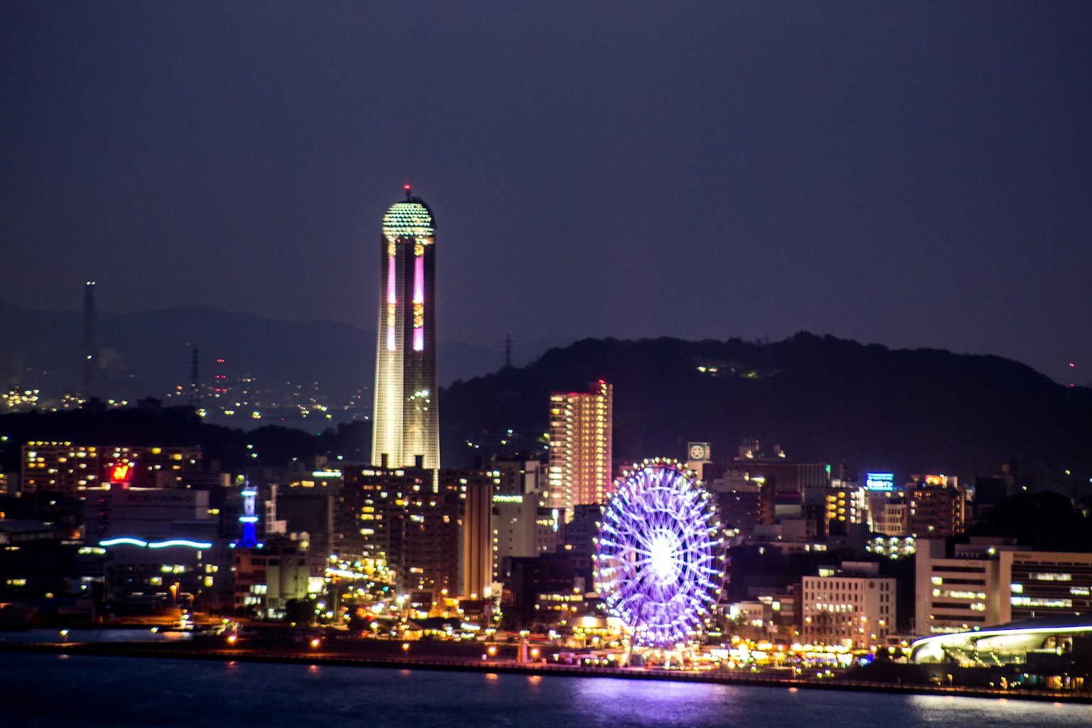 Silhouette de la ville illuminée la nuit avec une tour et une grande roue