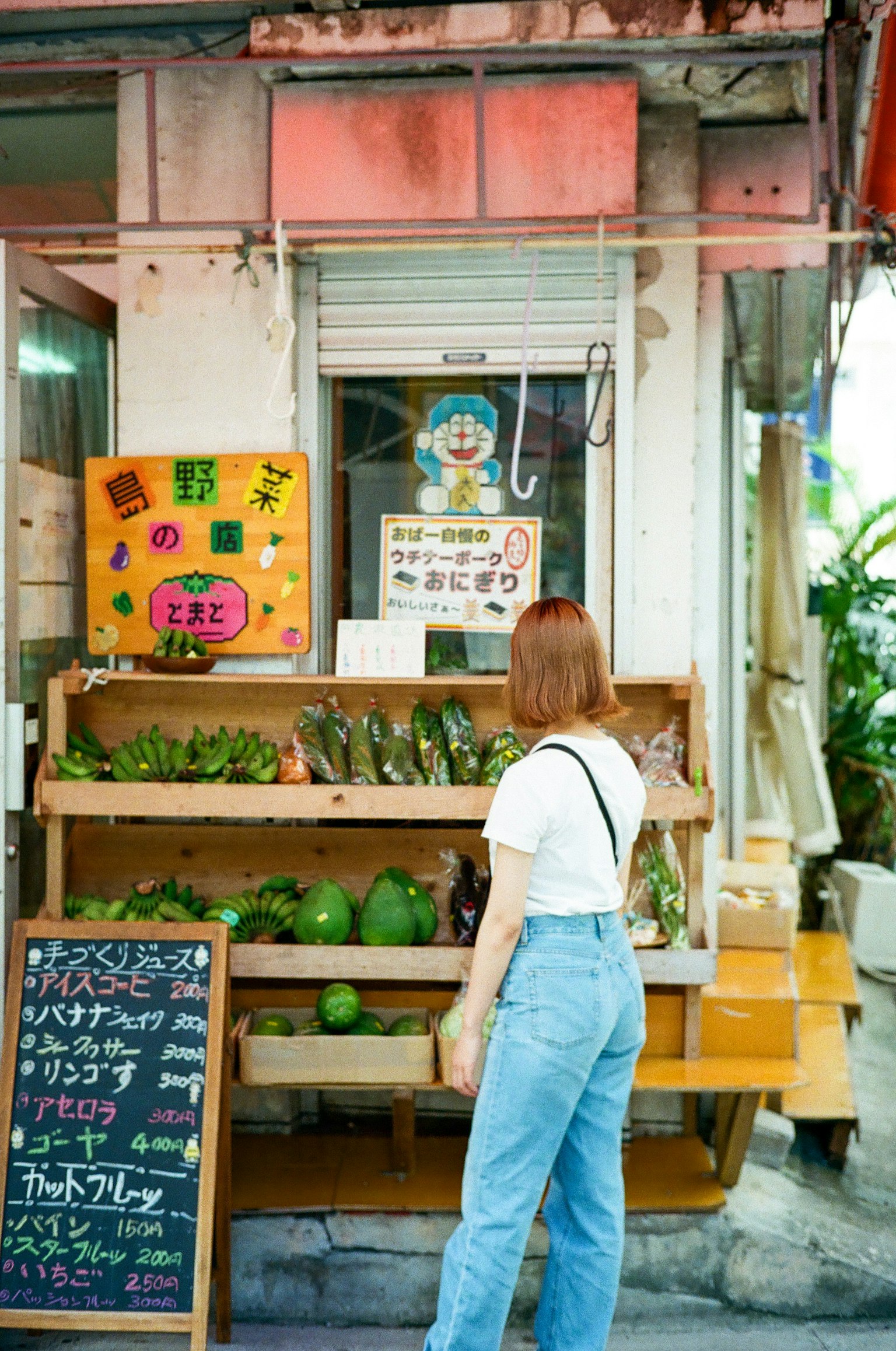 Một người phụ nữ đứng trước cửa hàng rau