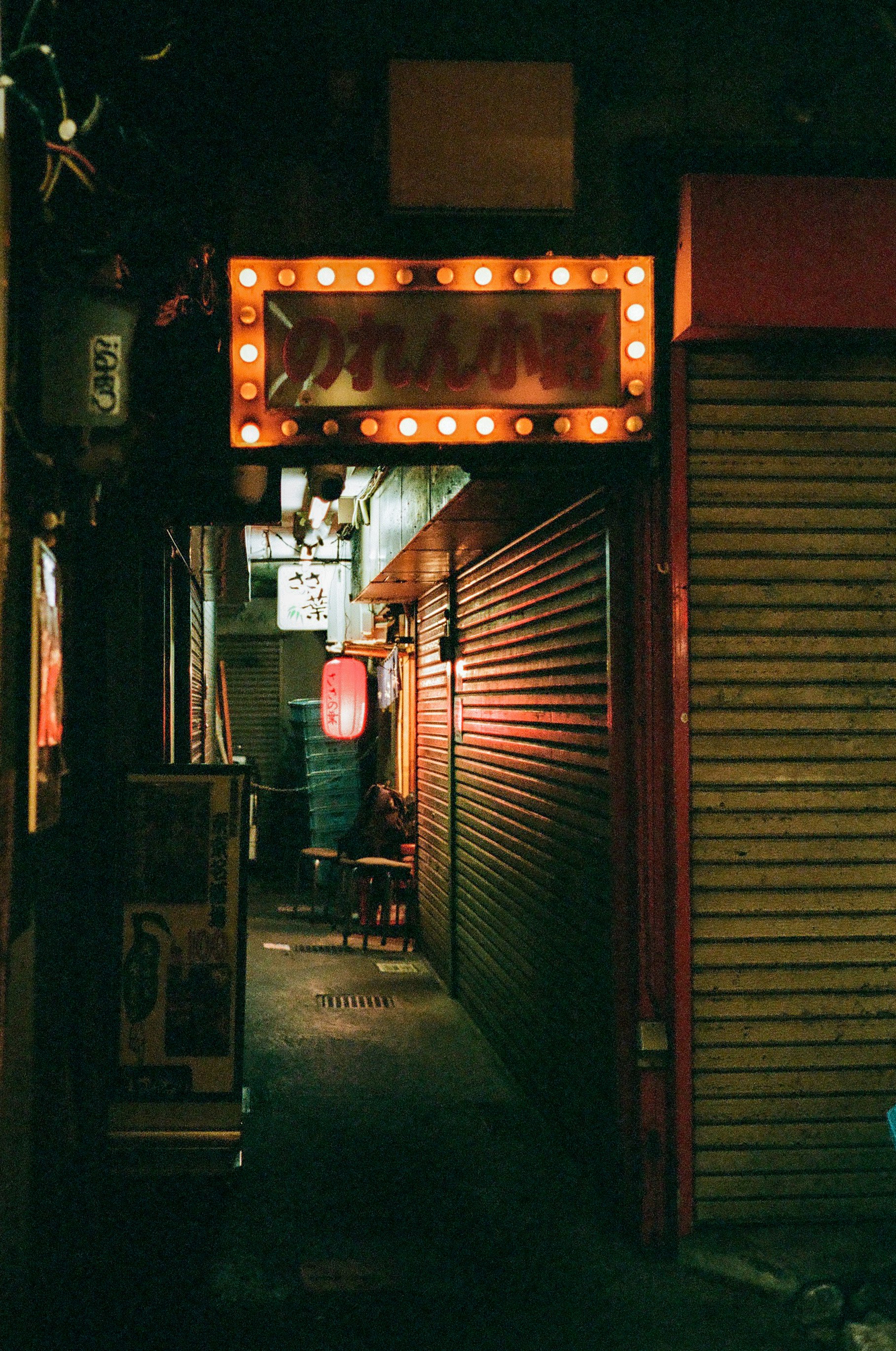 devantures de boutique dans une ruelle de nuit avec lanternes et volets fermés