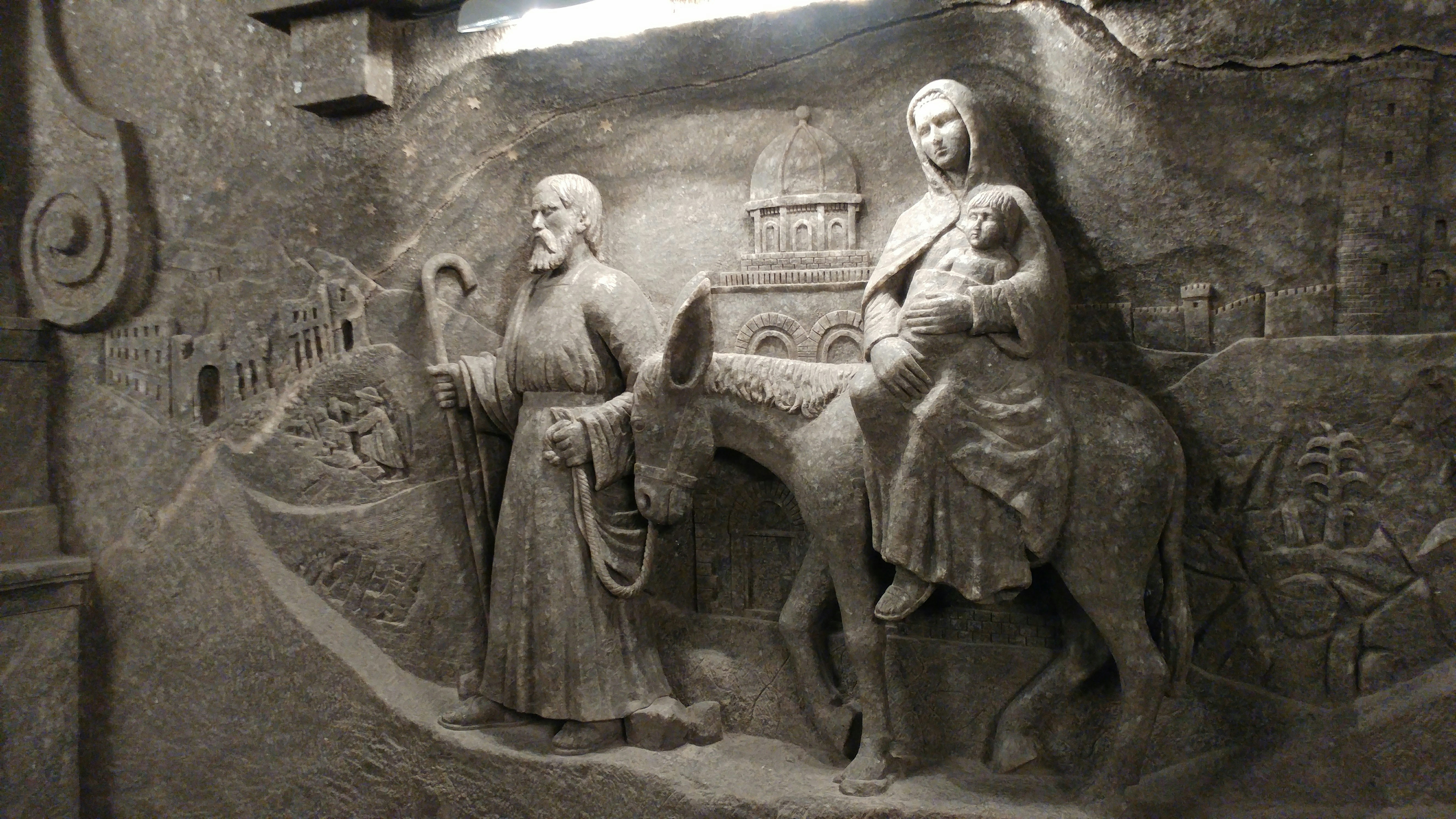 bassorilievo scolpito con figure e motivi architettonici su un muro immagine