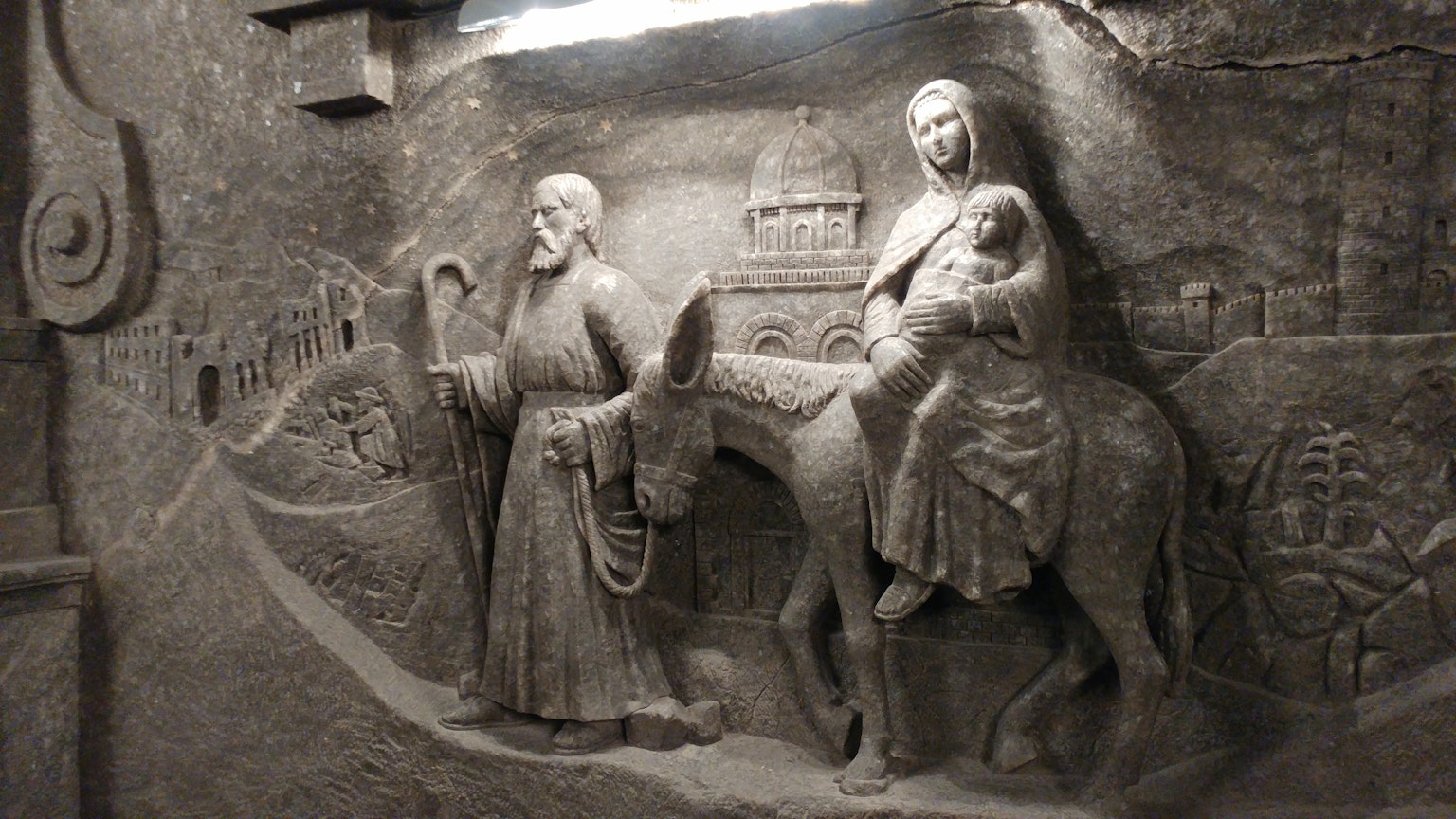 Mur en pierre sculpté représentant un voyageur et une femme tenant un enfant