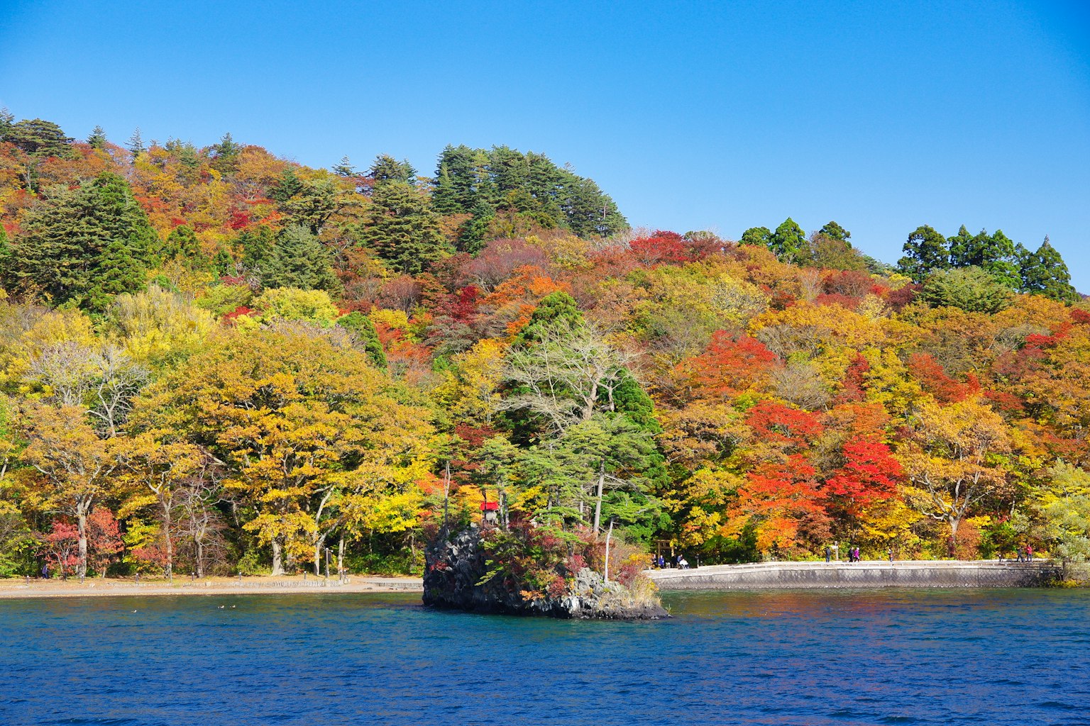 Bunte Herbstlaub um einen See unter klarem blauen Himmel