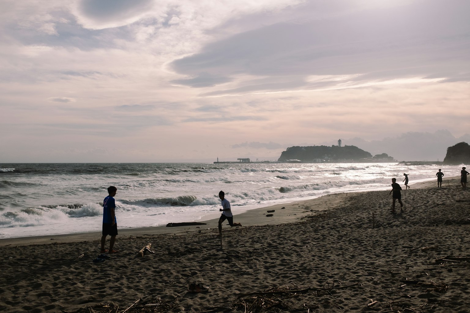 Niños jugando en la playa con olas y una isla a lo lejos