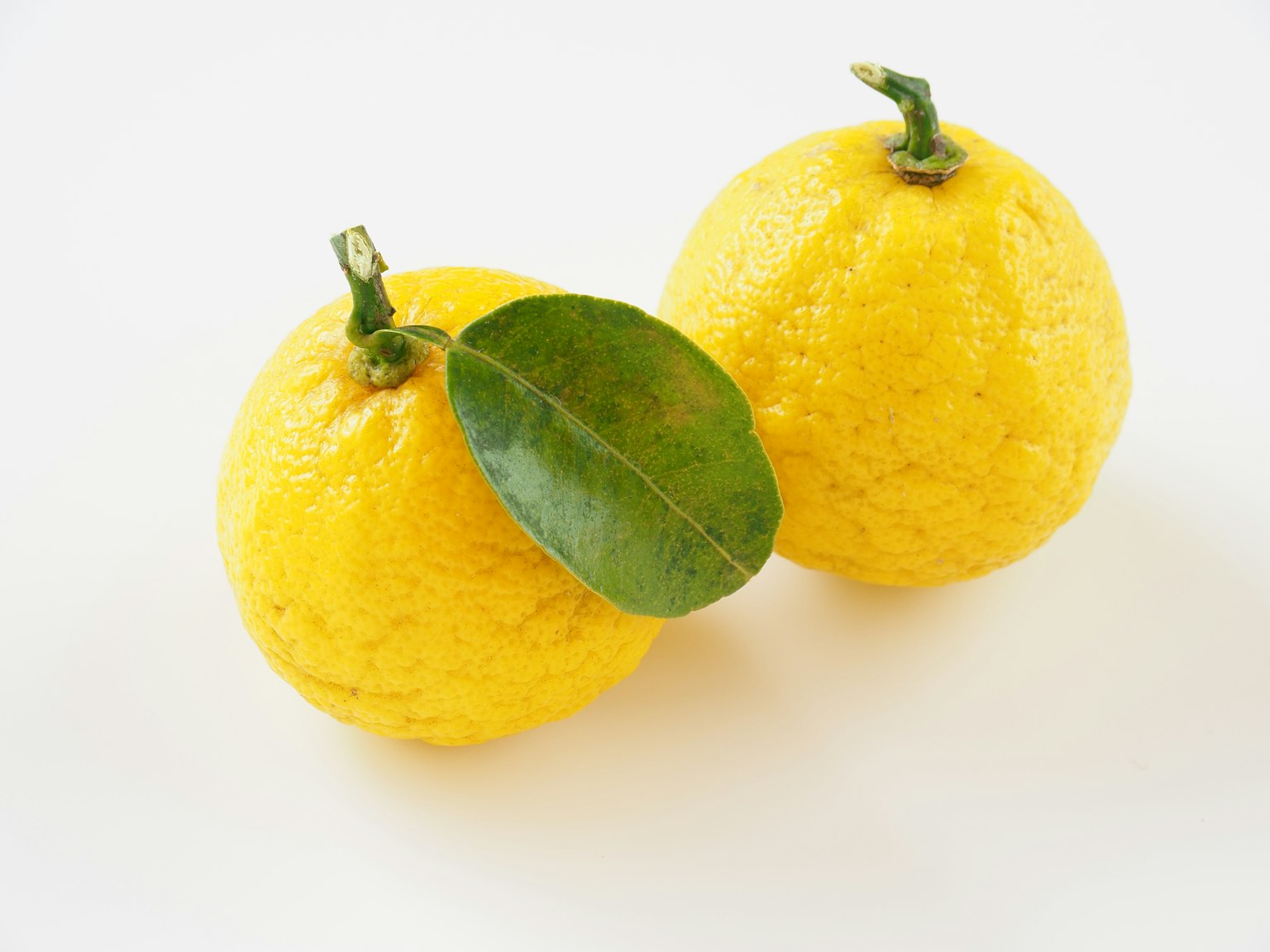 Due limoni gialli con una foglia attaccata