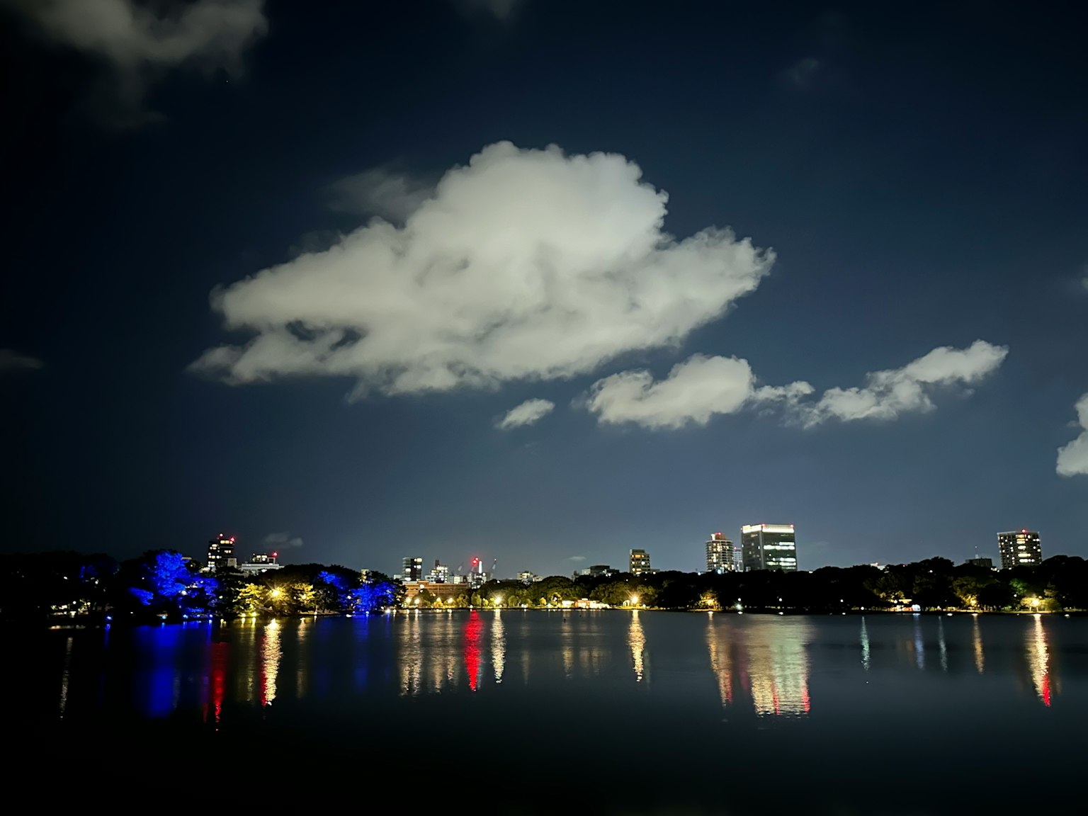 Luci della città che si riflettono su un lago di notte con nuvole