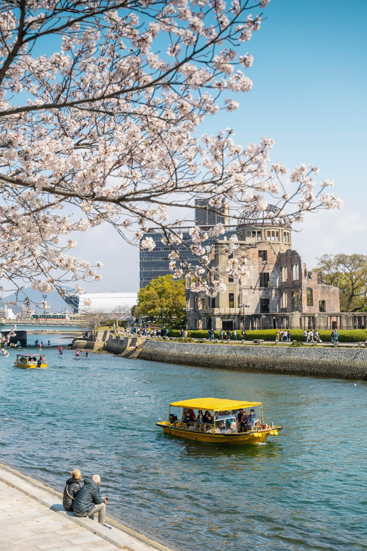 Cerezos en flor a lo largo de la orilla en Hiroshima con un bote amarillo