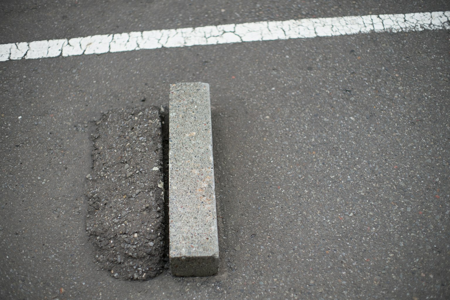 Concrete block placed on a cracked asphalt road with a white line