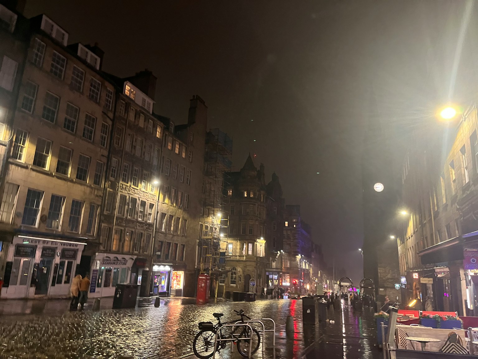 Calle de Edimburgo por la noche con faroles brillantes y pavimento de adoquines mojados