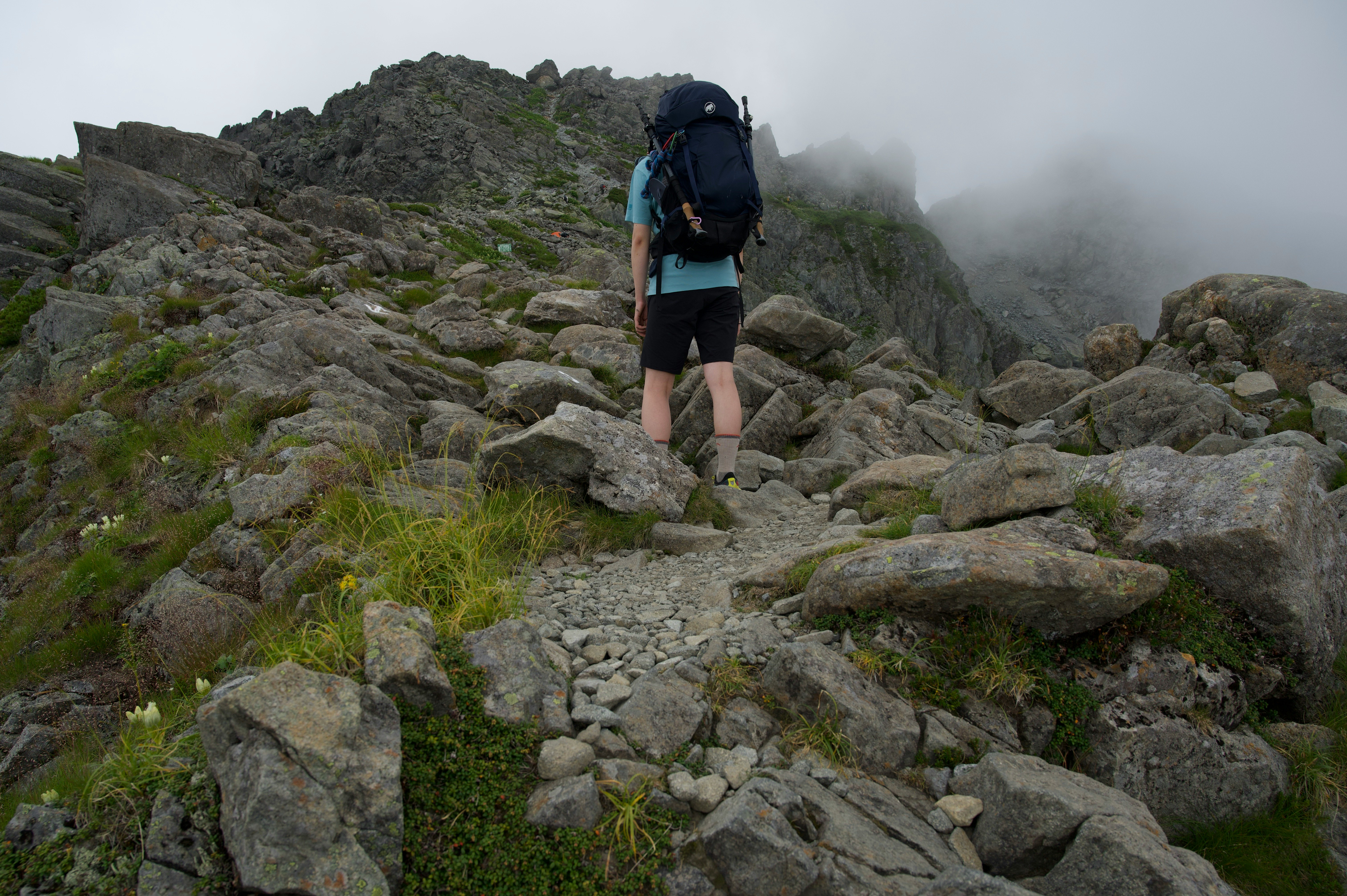 randonneur marchant sur un sentier rocheux dans la brume