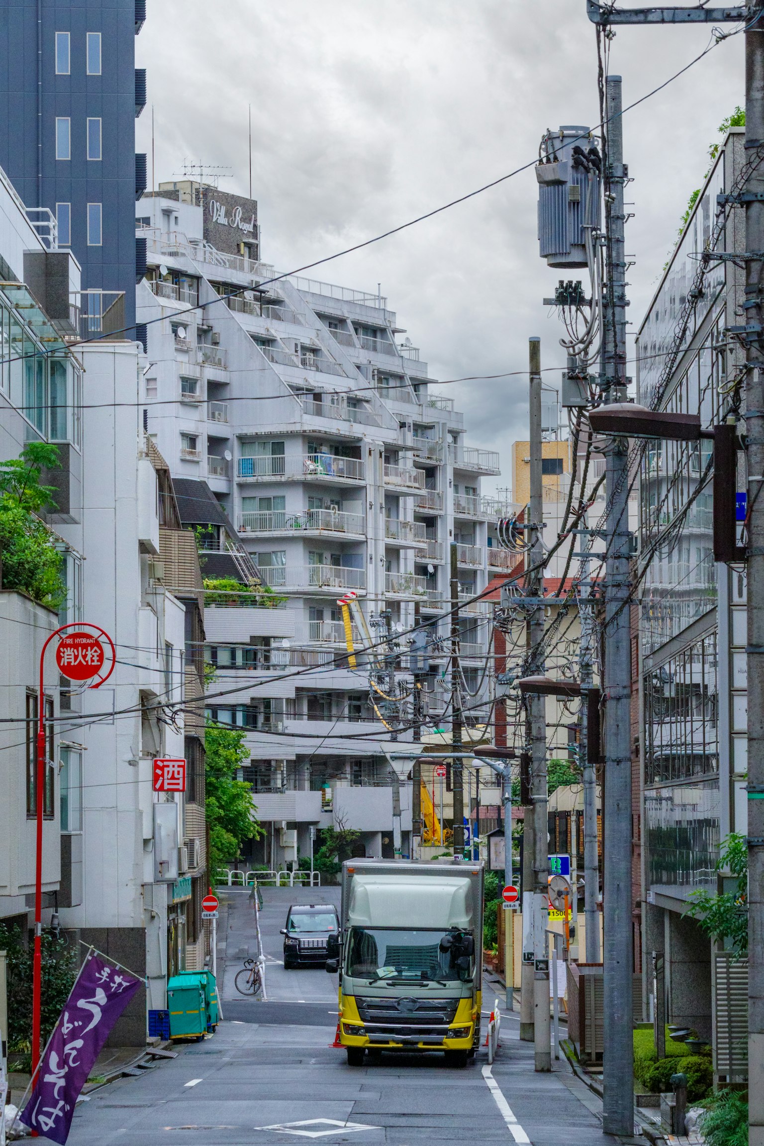 Ein Lkw fährt eine von Gebäuden gesäumte Stadtstraße unter bewölktem Himmel