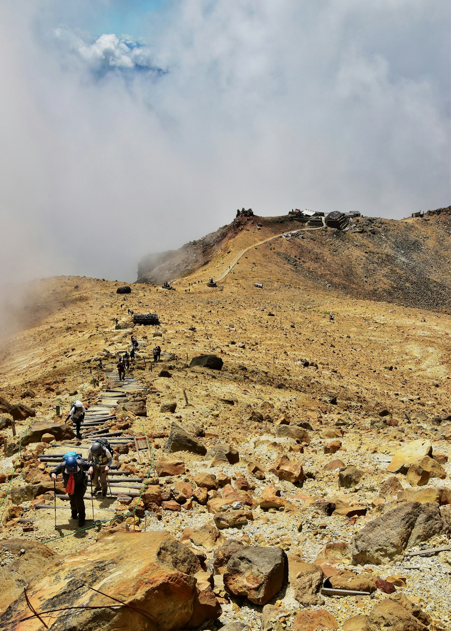 구름이 있는 배경의 바위 산길을 걷는 등산객들