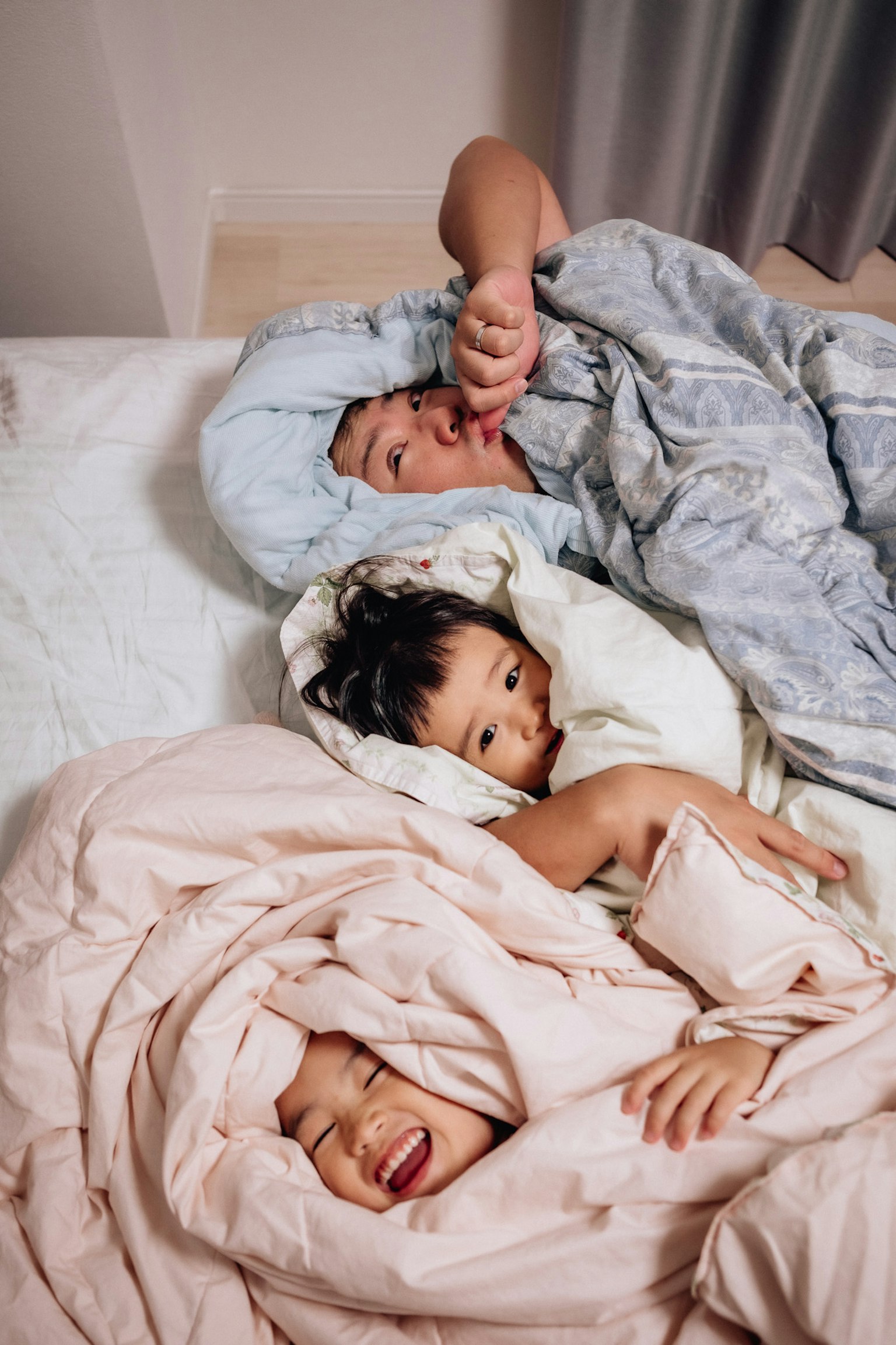 Una familia relajándose en la cama niños sonriendo envueltos en mantas