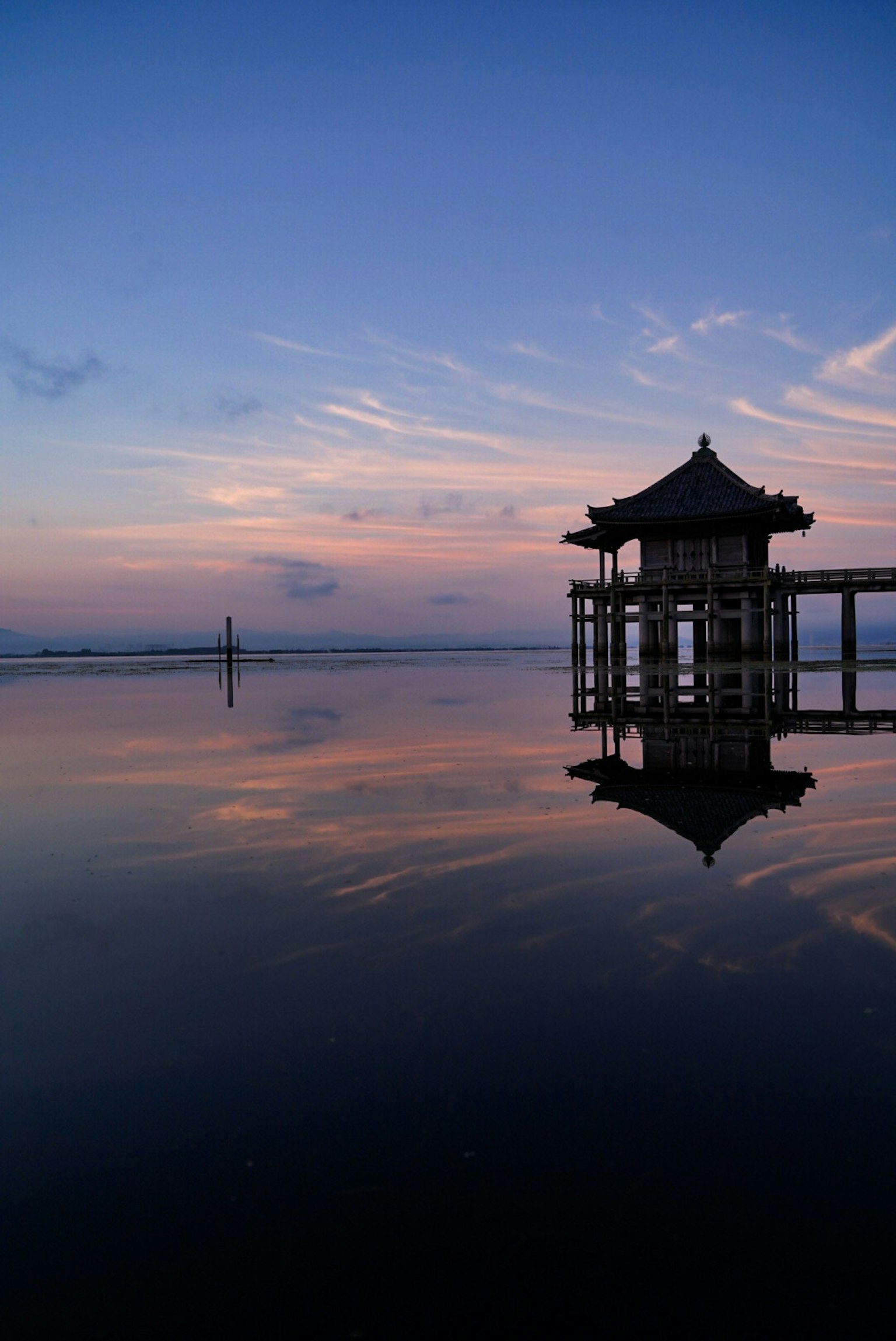 Pavilion reflecting on calm water during sunset