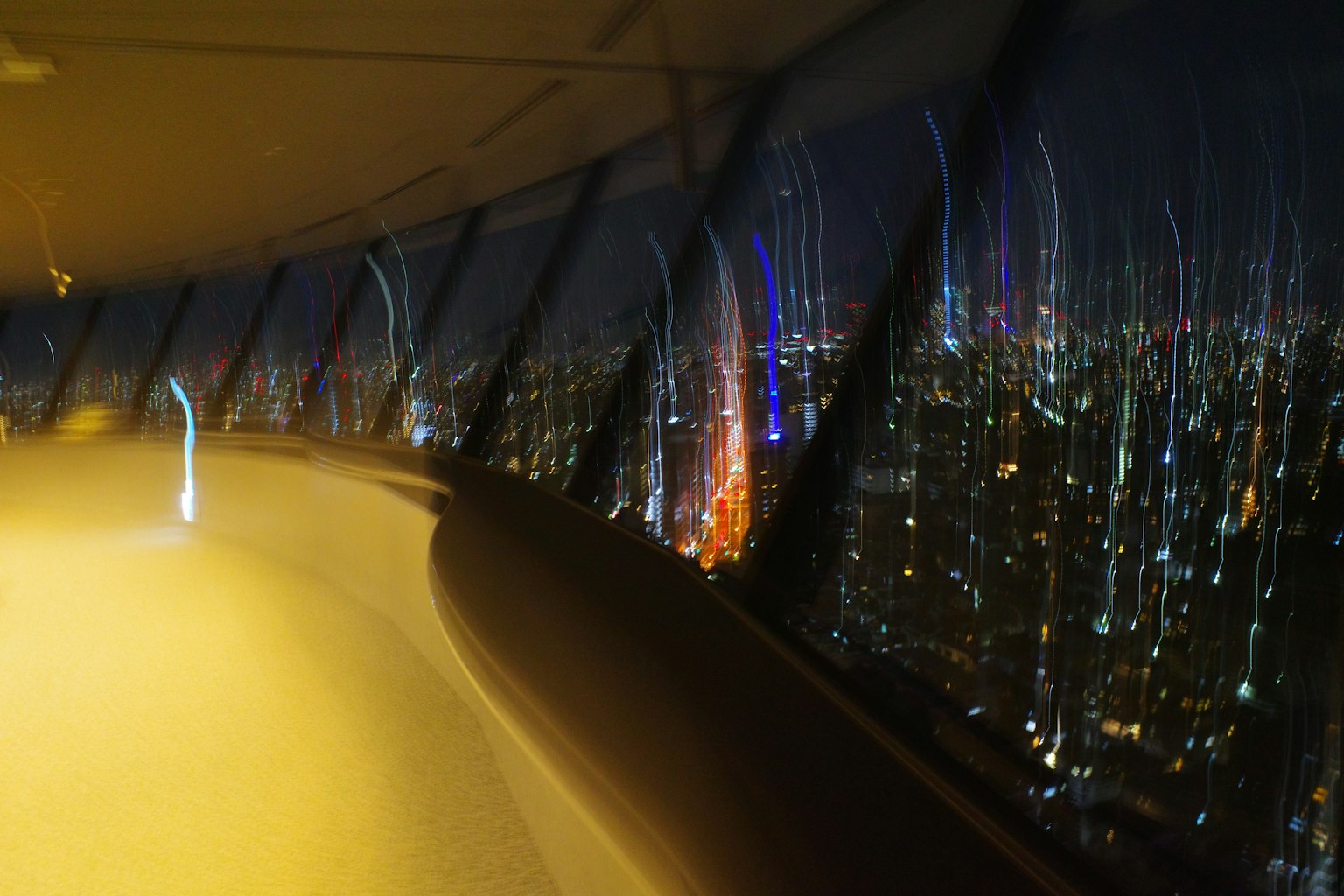 夜景が広がる展望台の内部 ぼやけた光の線が見える