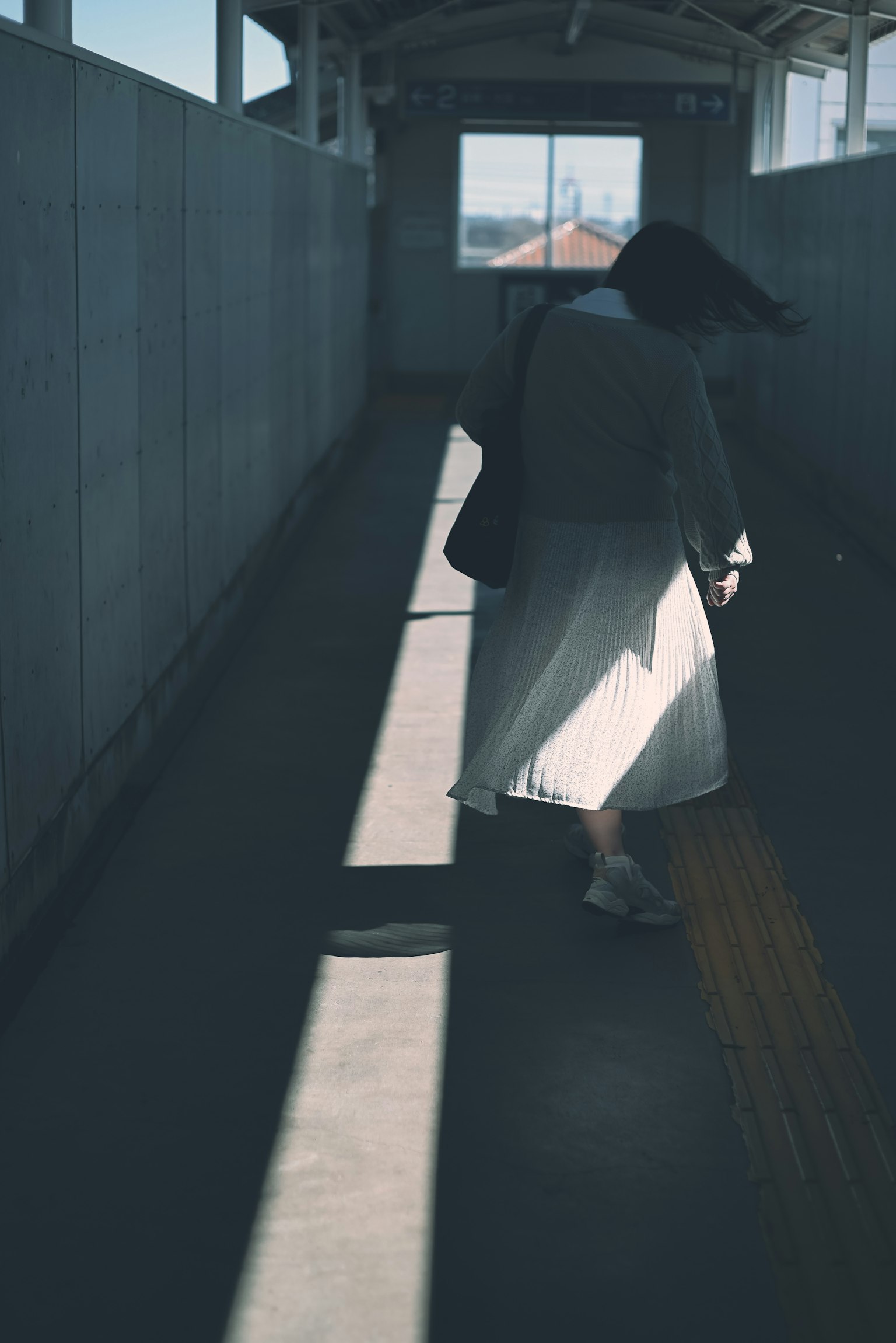 Silhouette di una persona che cammina in un corridoio debolmente illuminato con contrasto di luce