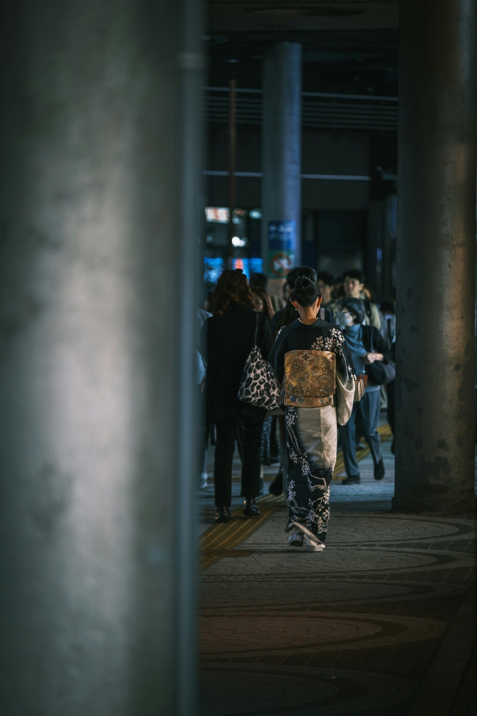 Une personne en kimono marchant dans une rue animée de la ville la nuit entourée d'autres