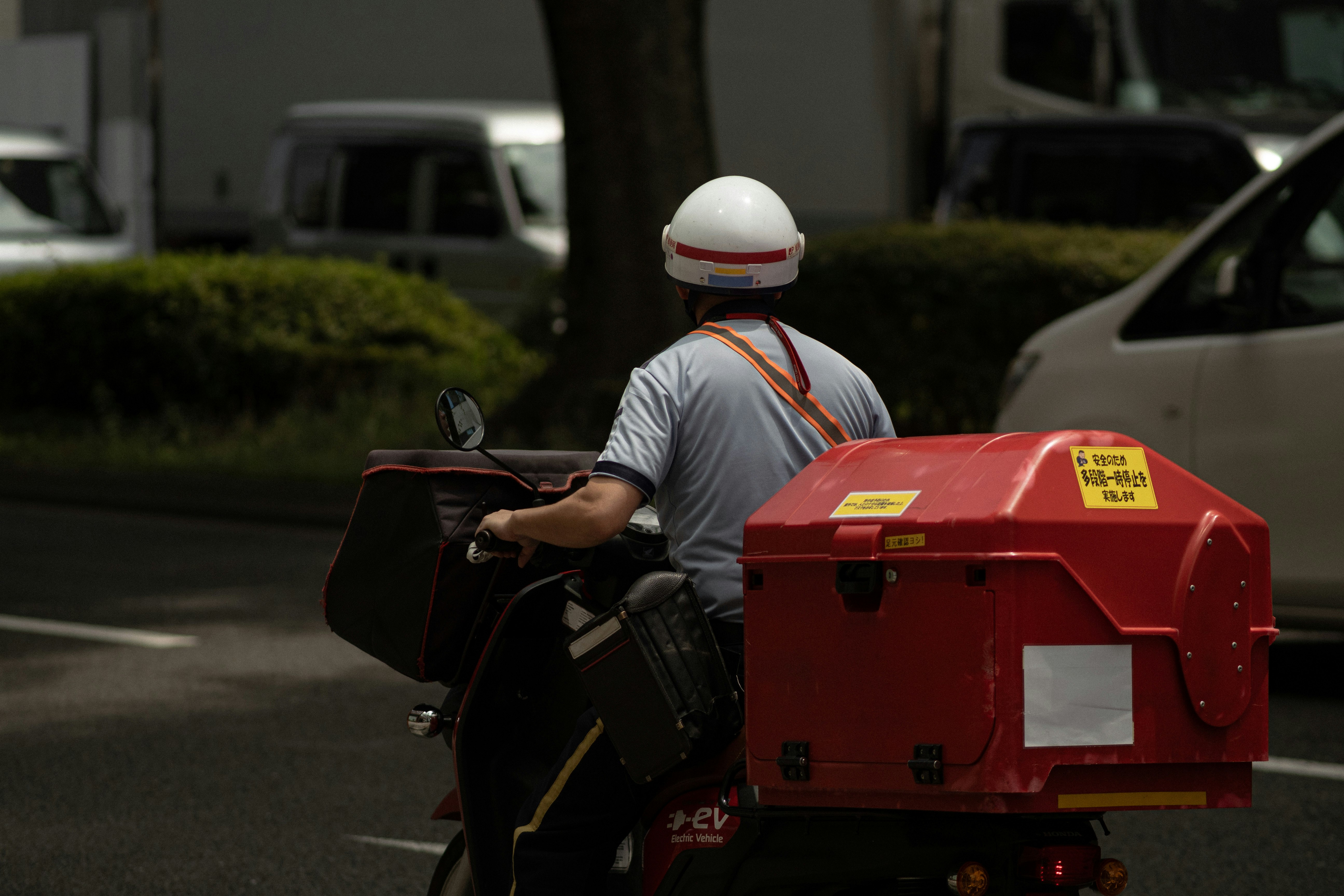 路上で働く配達員と赤い配送ボックス
