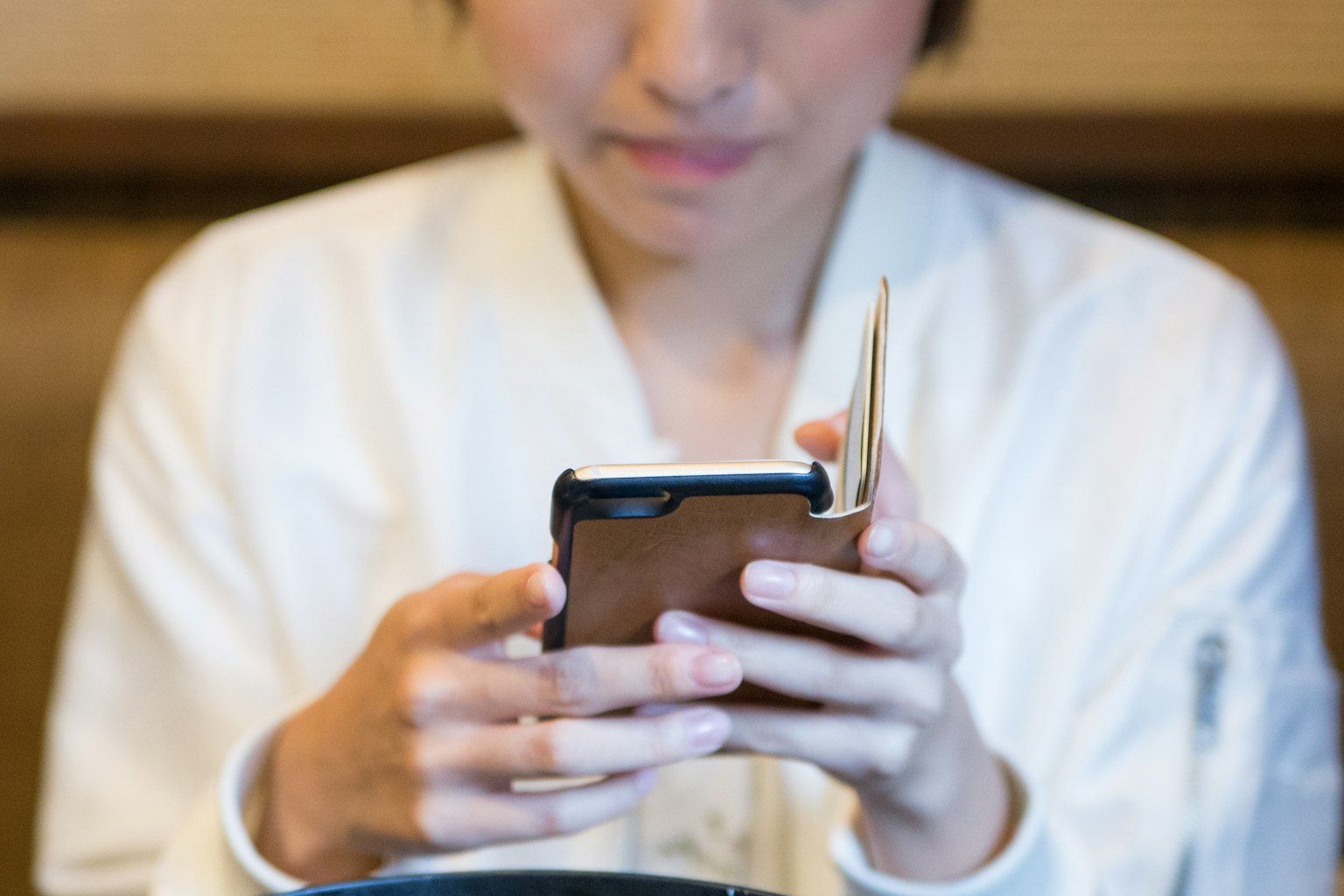 Una mujer con chaqueta blanca usando un smartphone