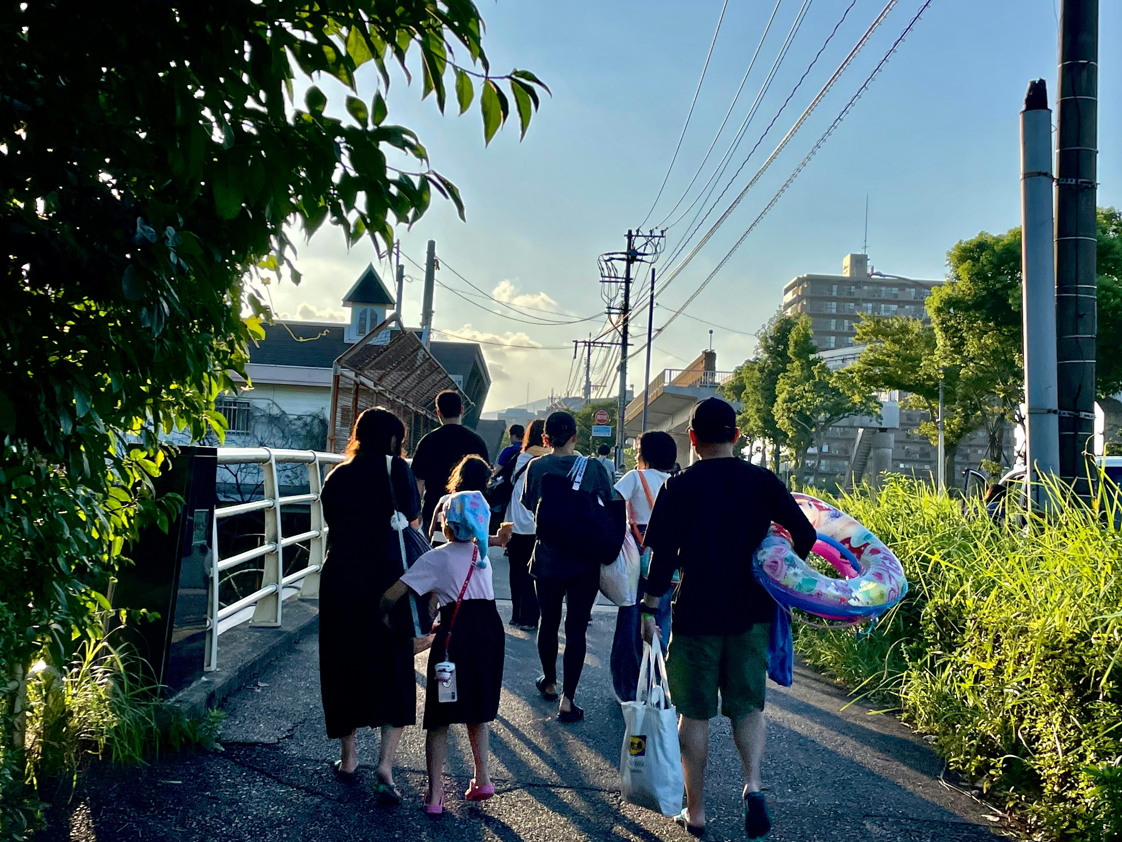 family walking home from the pool down a lane at dusk