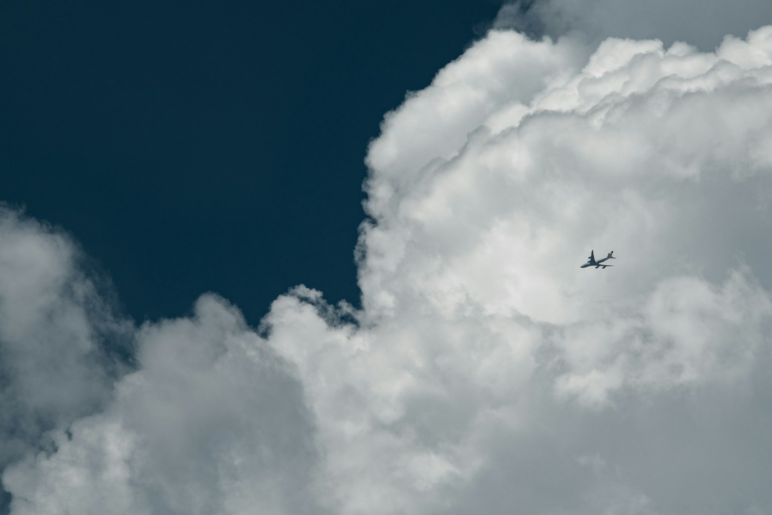 Flugzeug fliegt zwischen weißen Wolken vor blauem Himmel