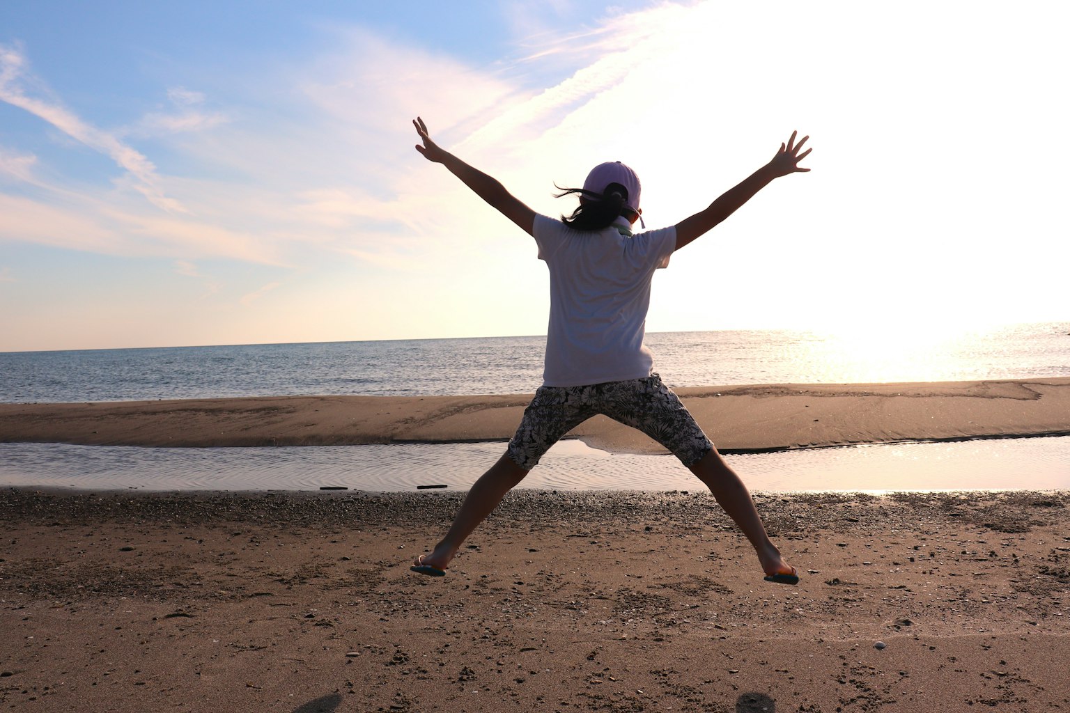 ビーチでジャンプする人のシルエットと夕日の背景