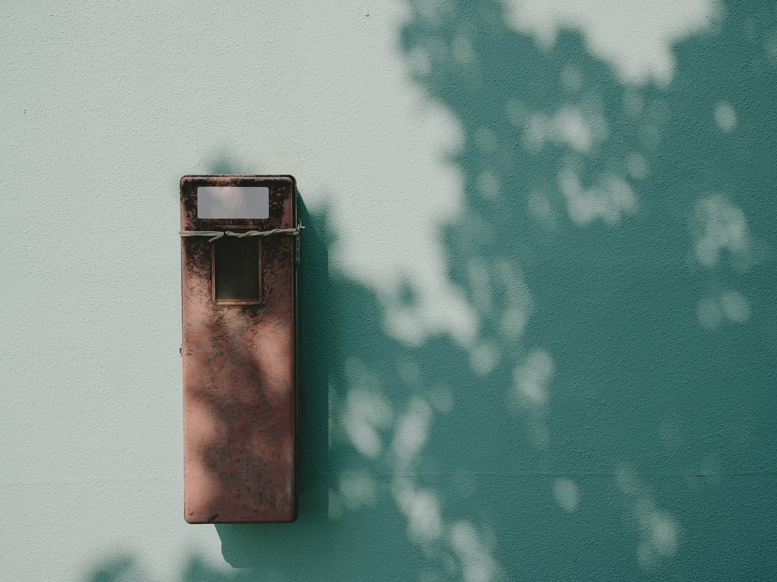 Vecchia cassetta postale montata su un muro teal con ombre morbide