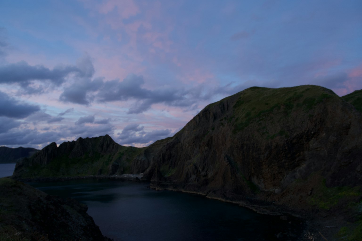 Paisaje al atardecer con montañas escarpadas y mar tranquilo