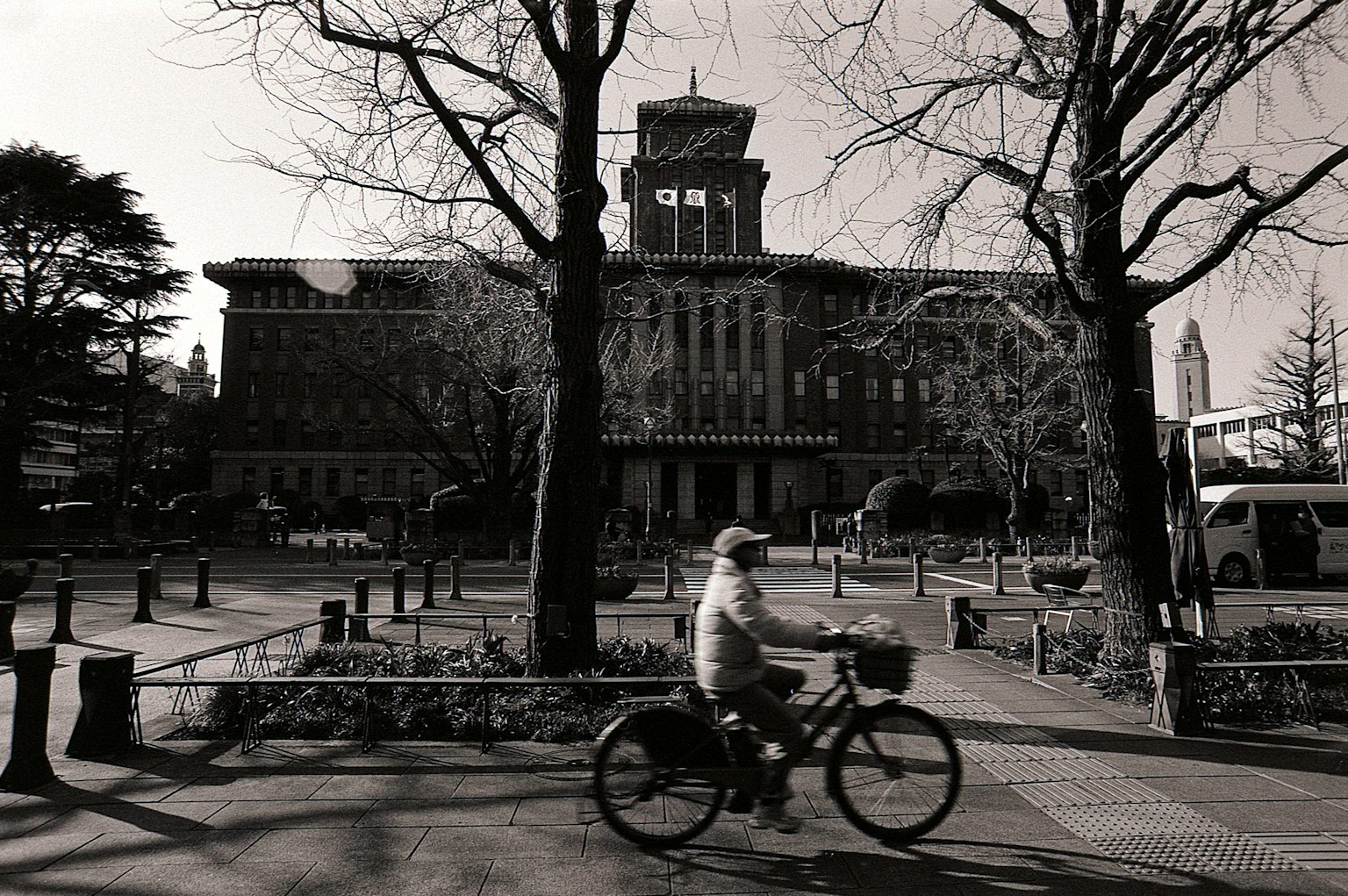 Un ciclista pasando por un parque con un edificio histórico al fondo