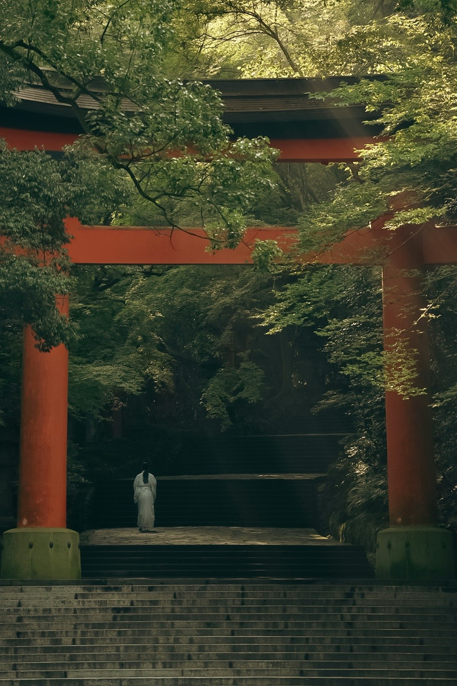 A serene scene of a person standing in front of a red torii gate surrounded by greenery