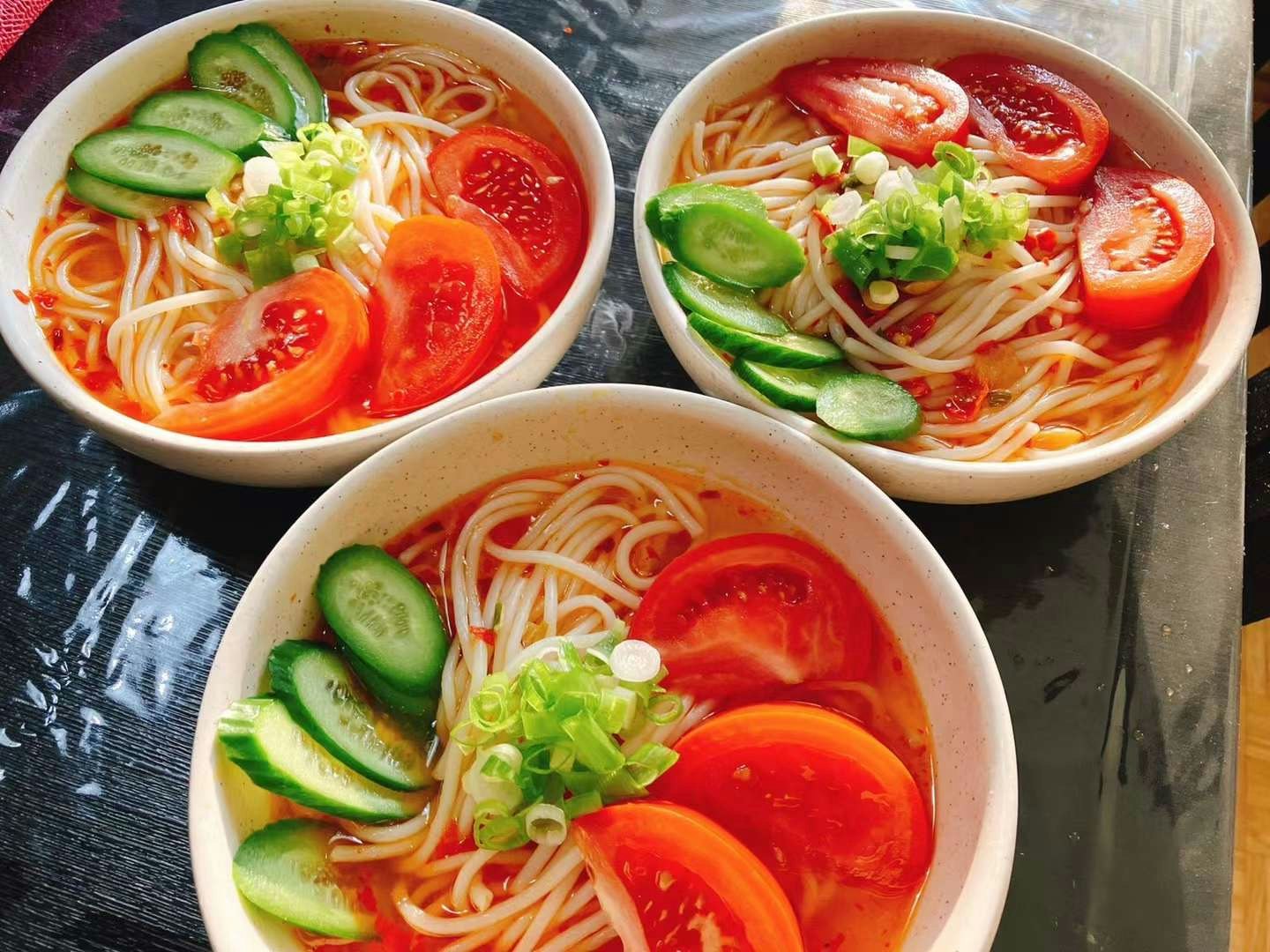 tre ciotole di zuppa di noodles con pomodoro e cetriolo