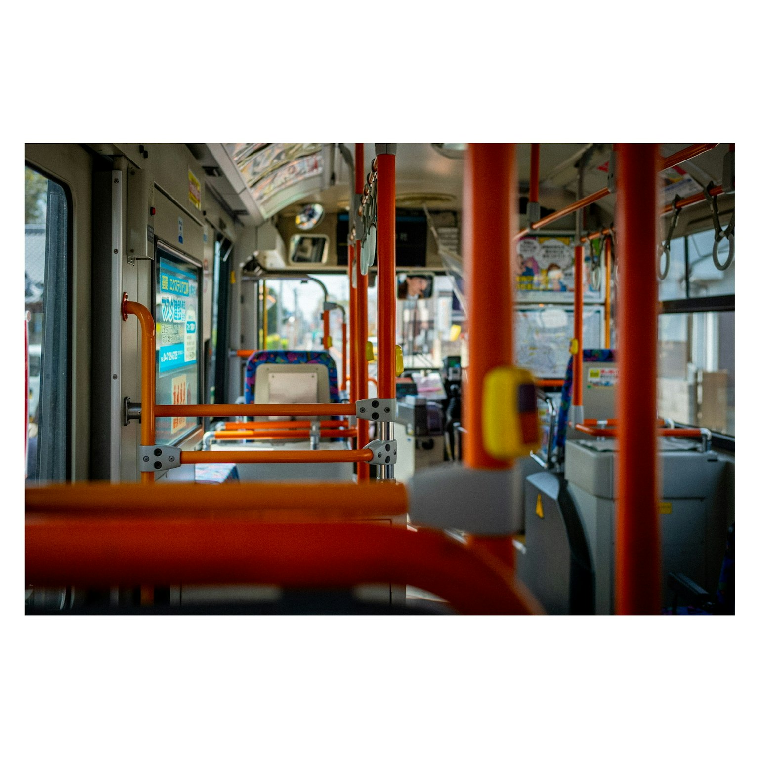 バスの内部の写真 赤い手すりと空席が見える