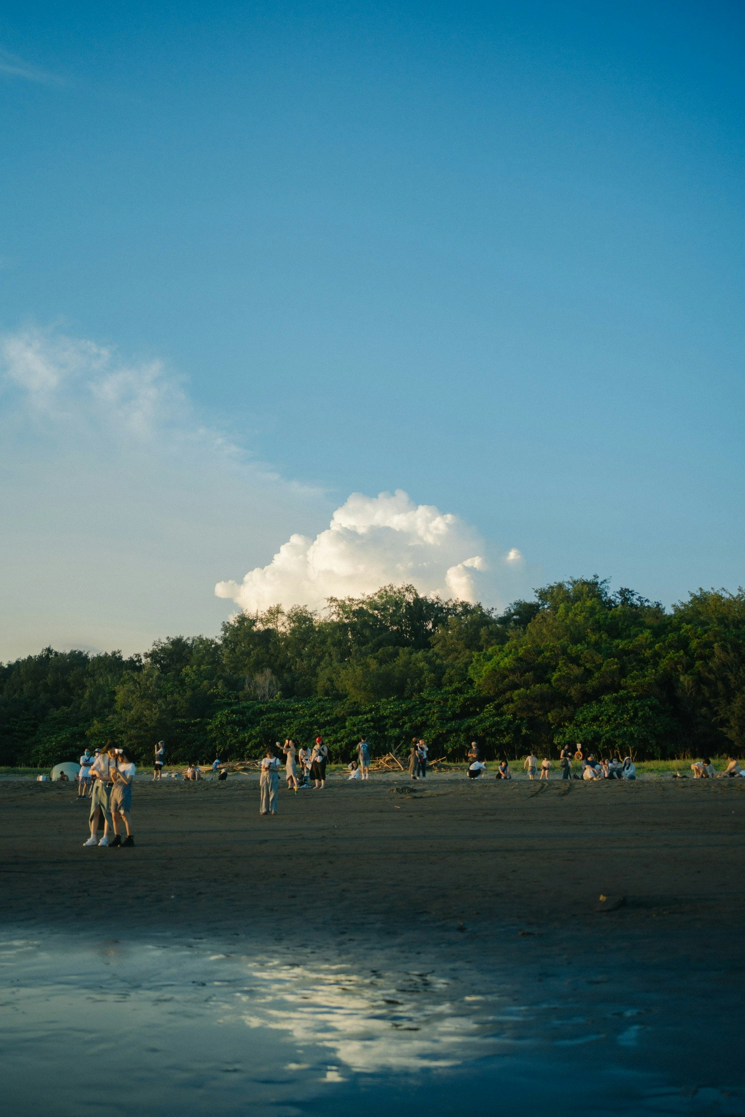 Menschen genießen eine Strandszene unter einem blauen Himmel mit weißen Wolken