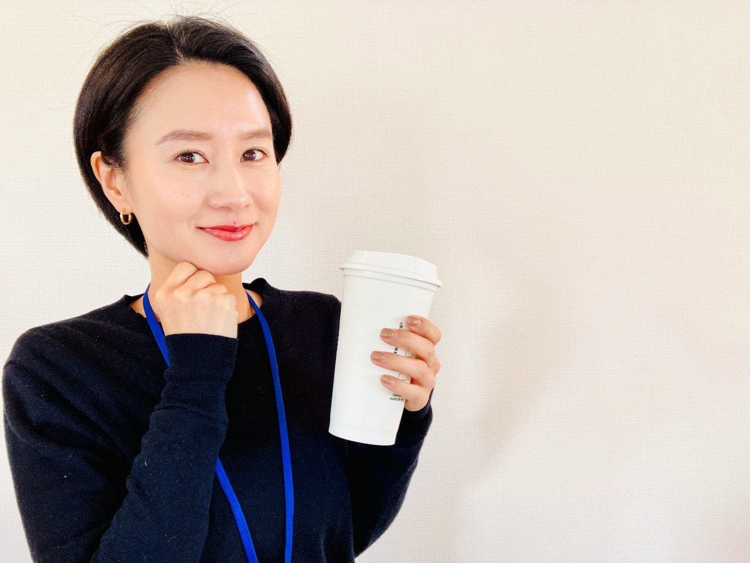 女性微笑着手持白色咖啡杯