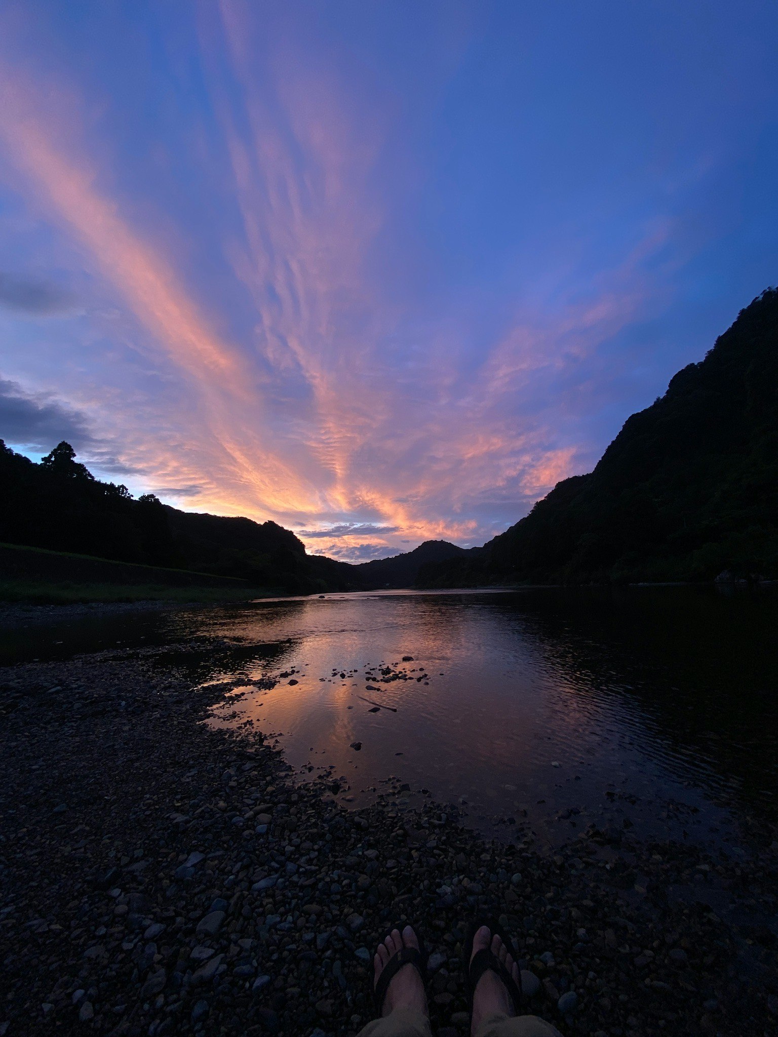 夕焼けの空と渓谷の川が流れる川辺の風景