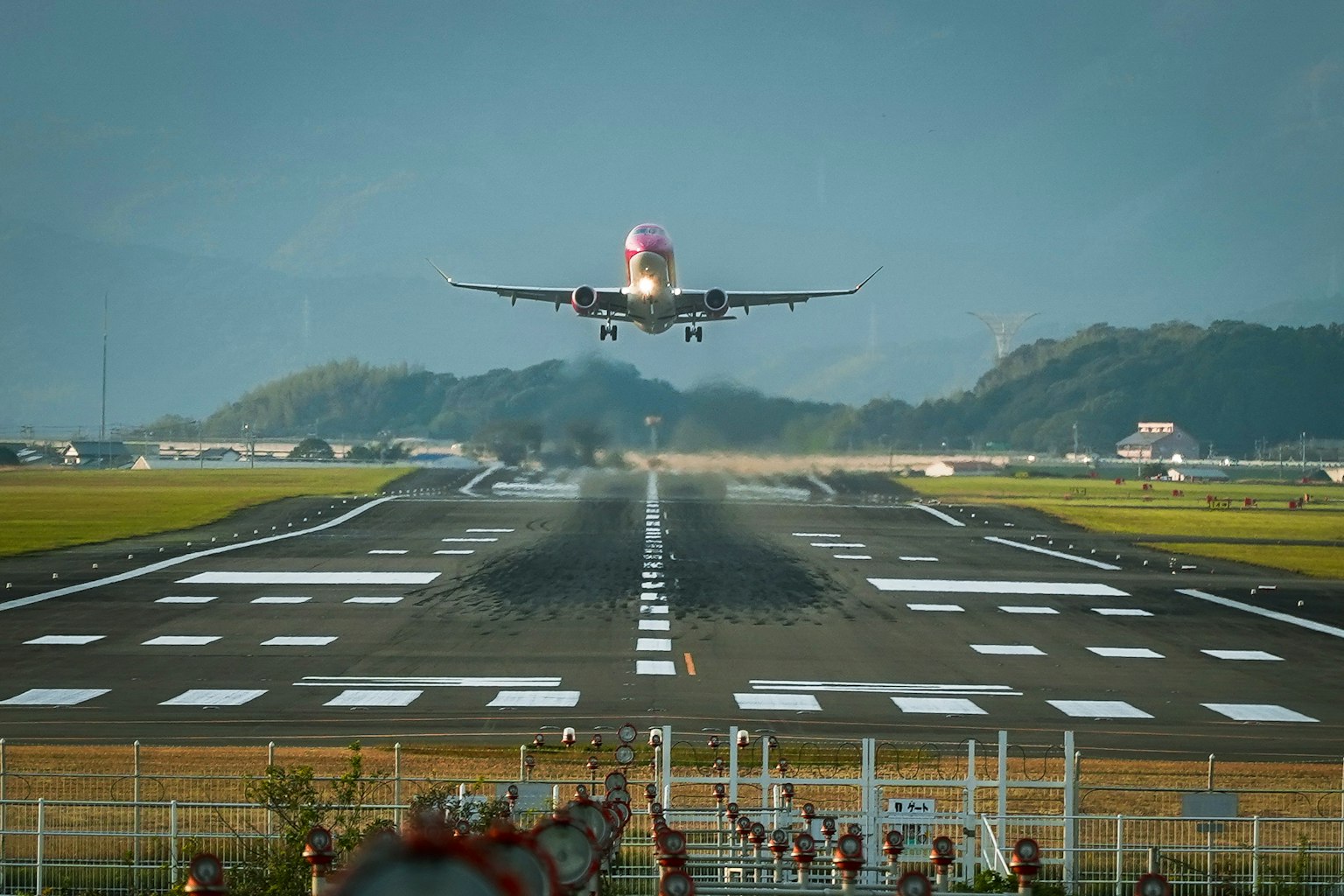 Airplane landing on runway with airport background and mountains in view