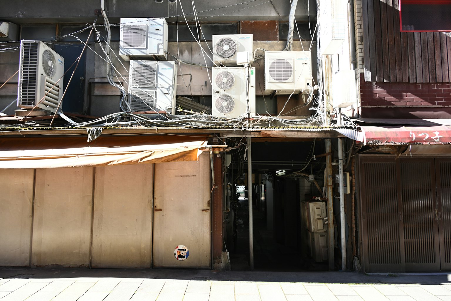 老舊建築的外觀，配有空調單元和關閉的捲簾