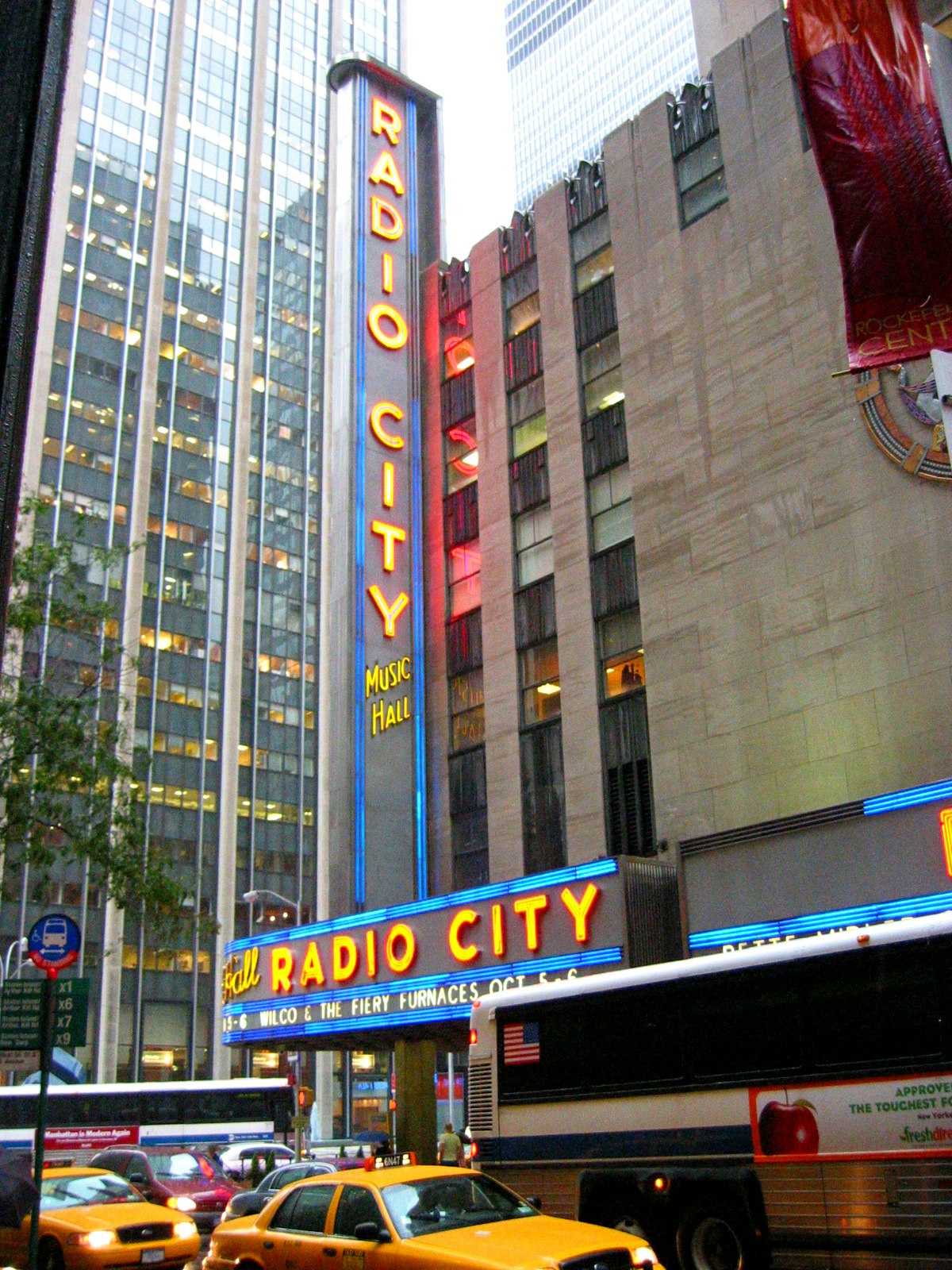「Radio City」招牌下的繁忙城市街道與樓群及車輛
