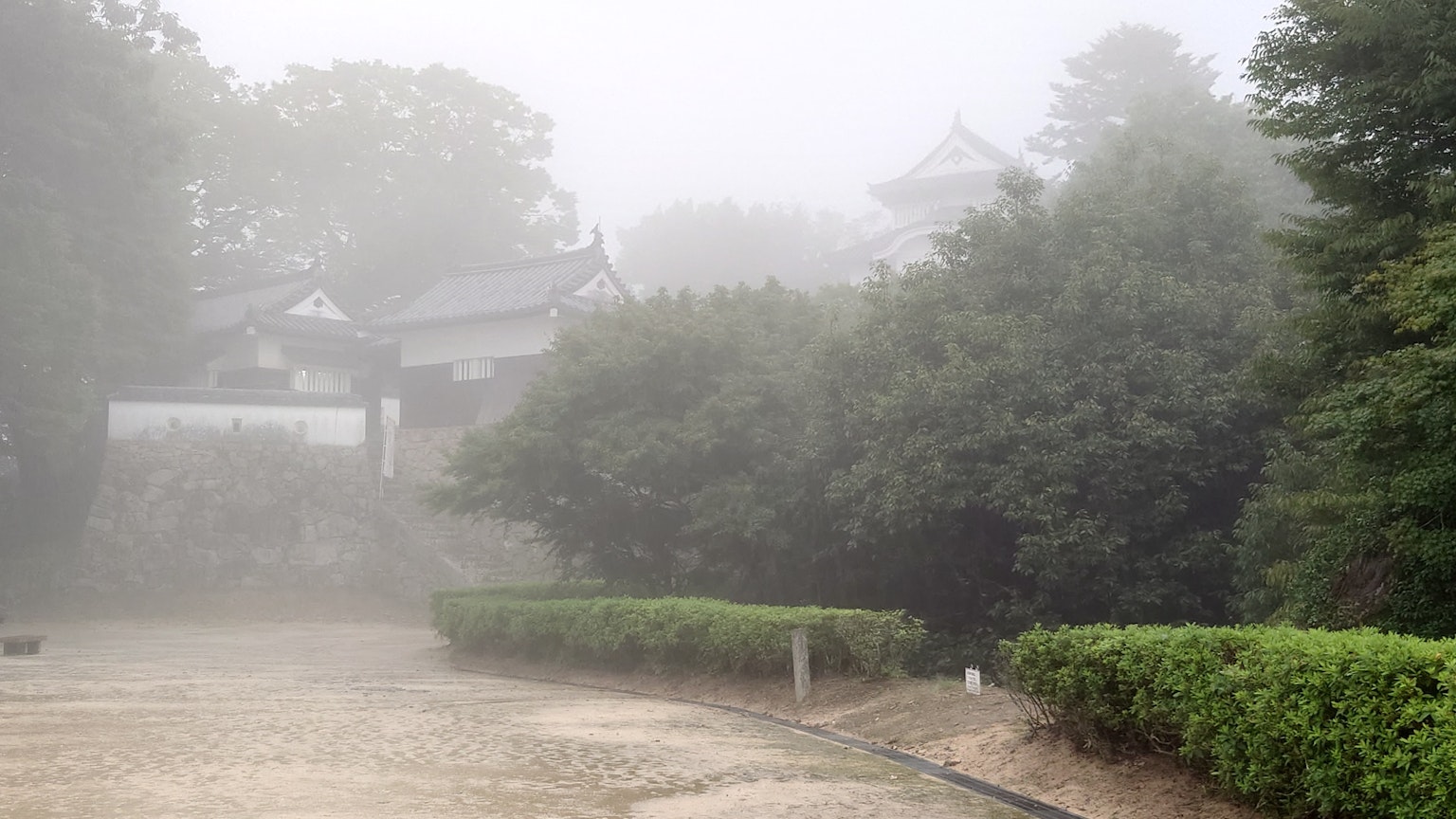 Pemandangan berkabut taman Jepang dengan bangunan tua di latar belakang