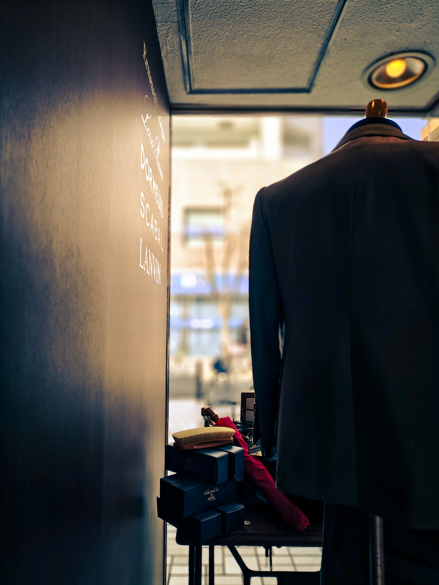 Un maniquí con un traje frente a una pared negra con accesorios de ropa en una mesa
