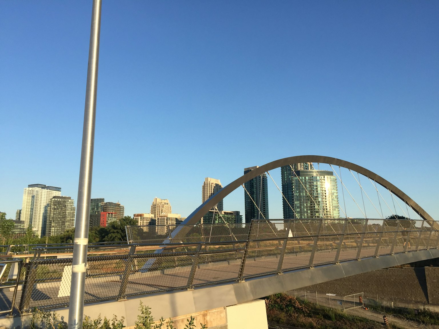 Moderner Bogenbrücke unter blauem Himmel mit Stadtsilhouette