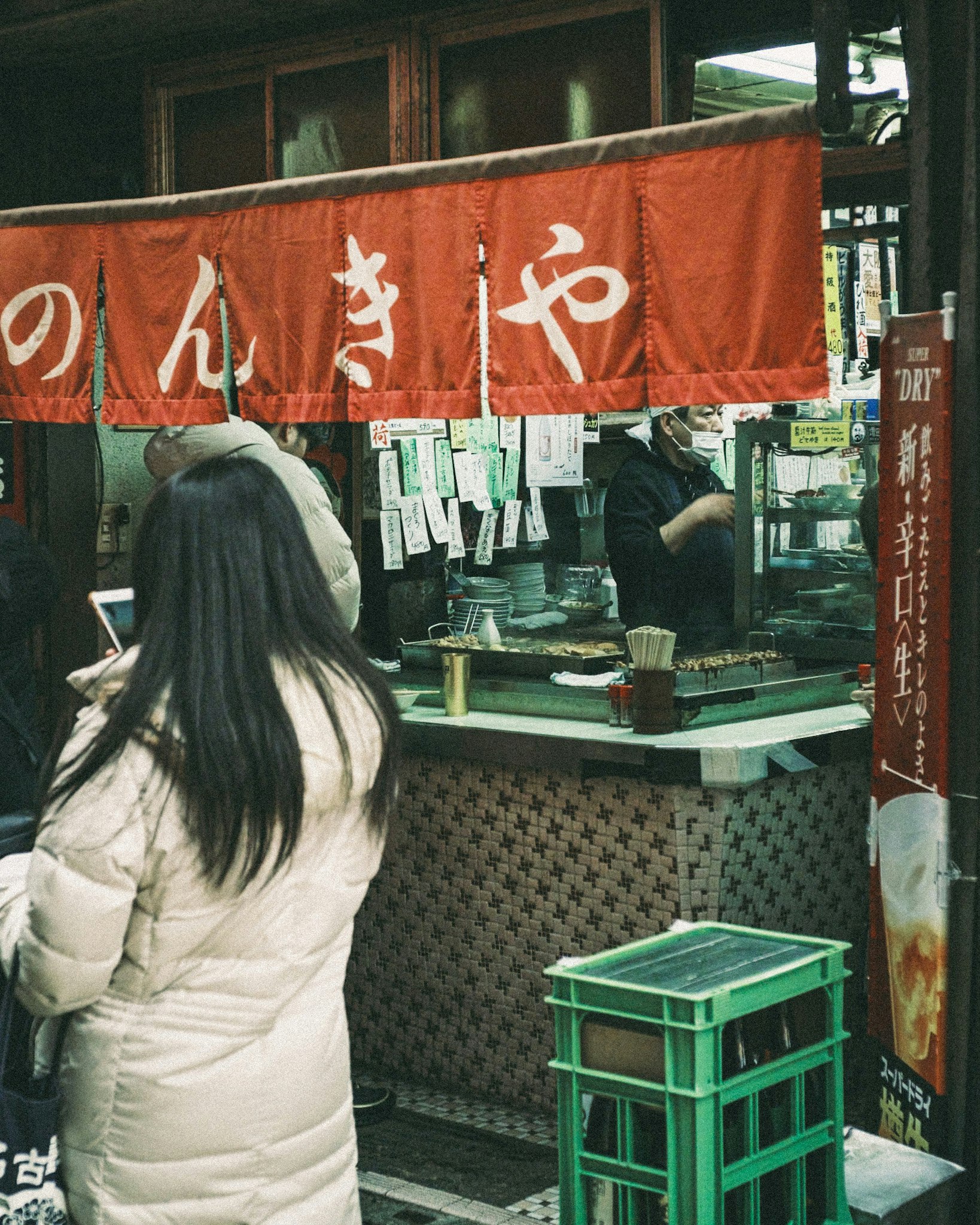 屋台の前でのんきに買い物する人と提灯のある和風商店街の軒先