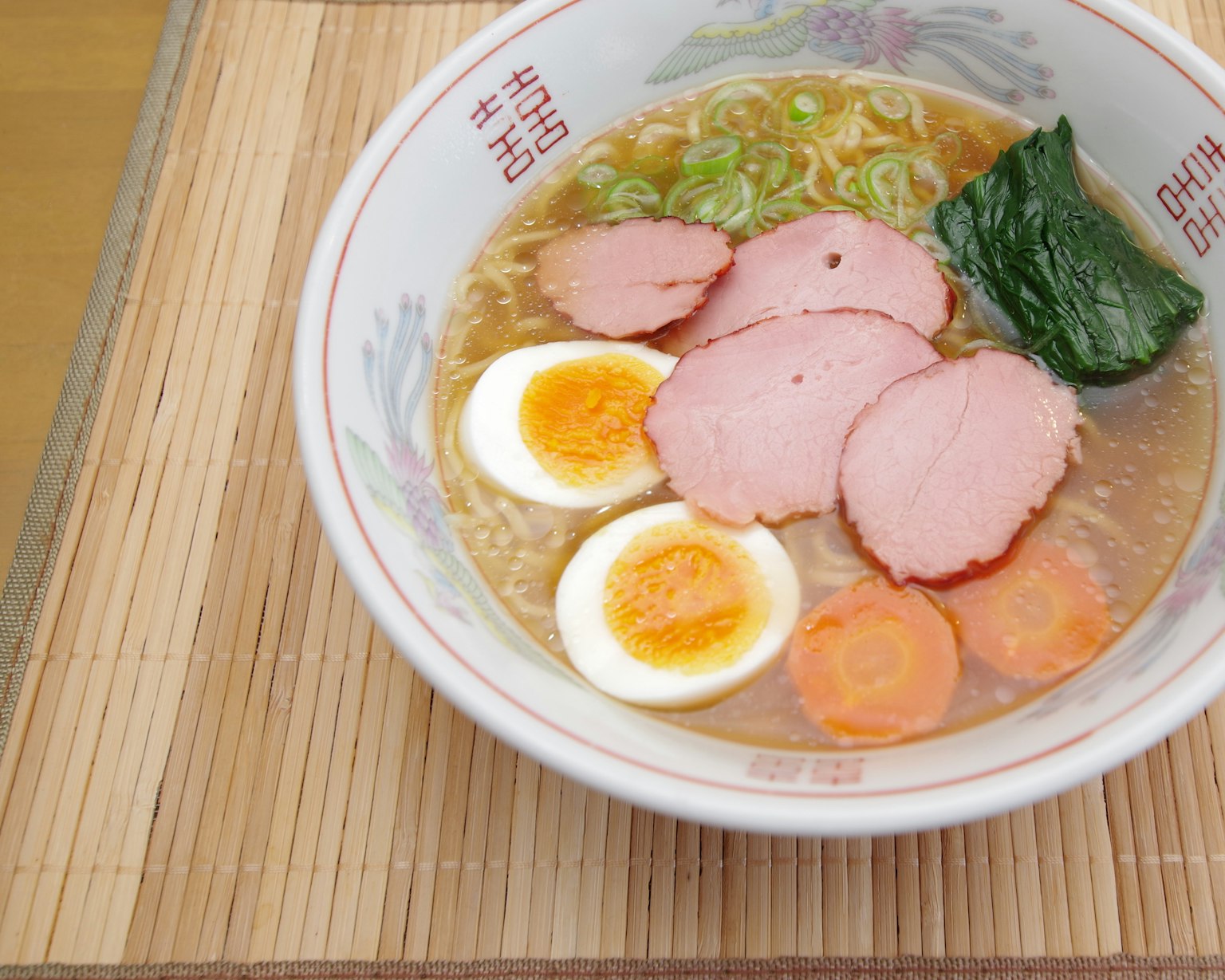 Một bát ramen với thịt chashu thái lát, trứng luộc, hành lá, rau chân vịt và cà rốt