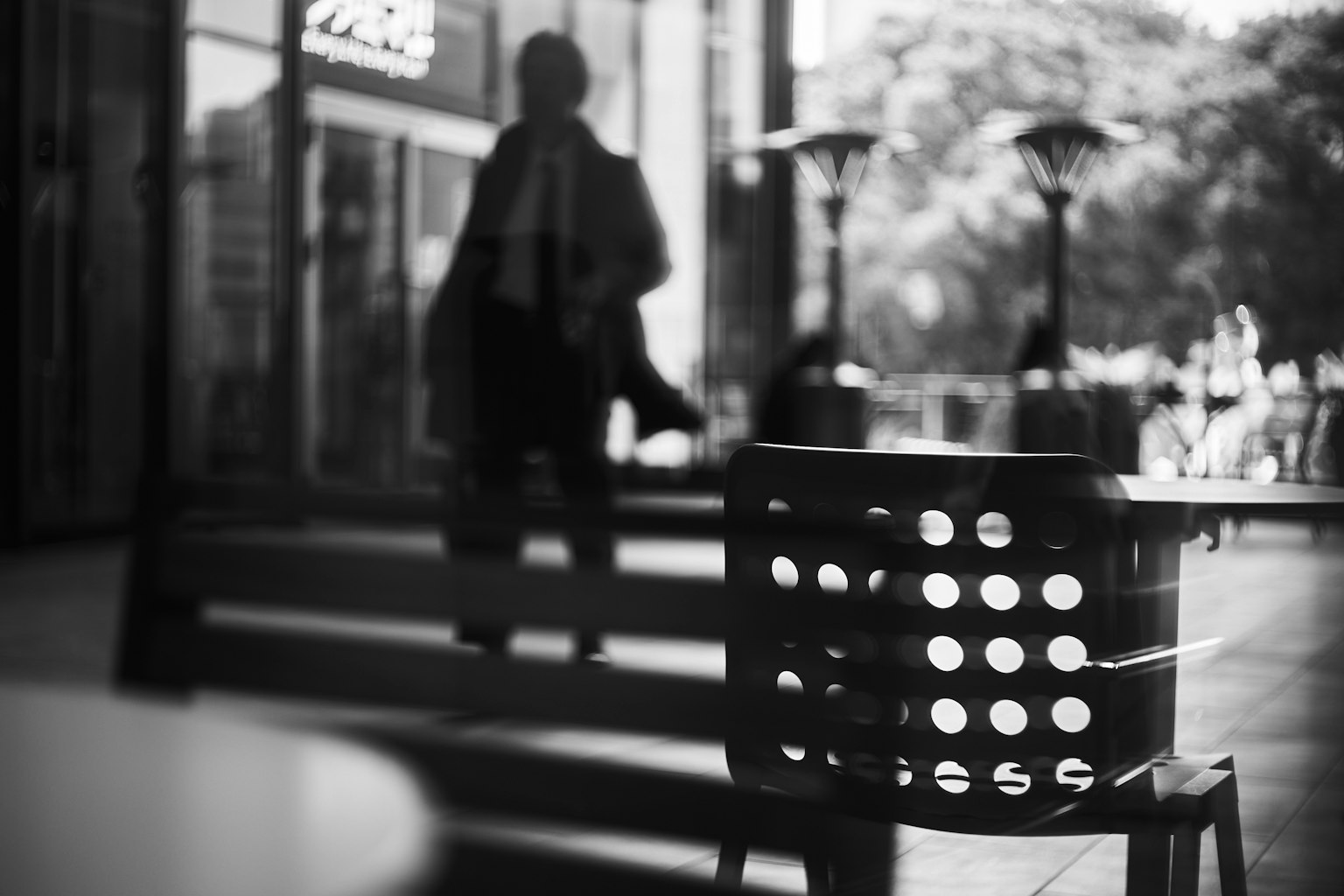 Image en noir et blanc d'une chaise à trous avec une silhouette floue en arrière-plan