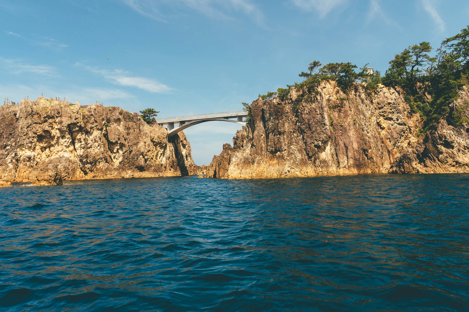 Vista escénica de una costa rocosa con un puente sobre agua turquesa