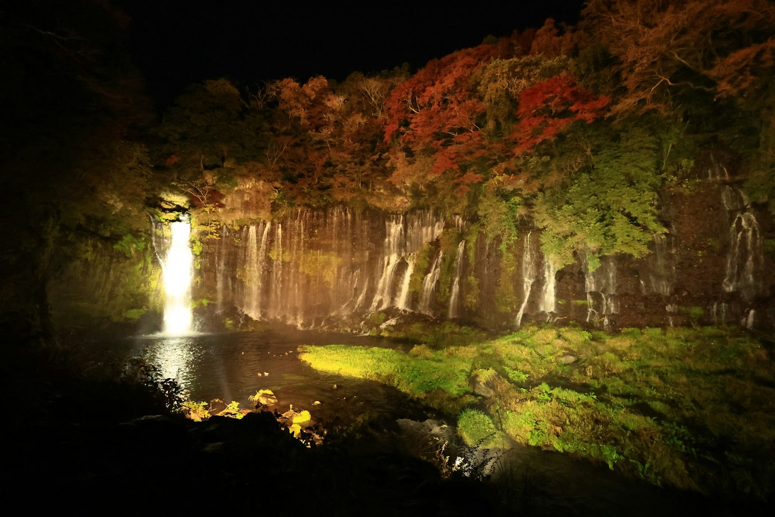 Un paysage nocturne serein avec une cascade entourée de feuillage automnal