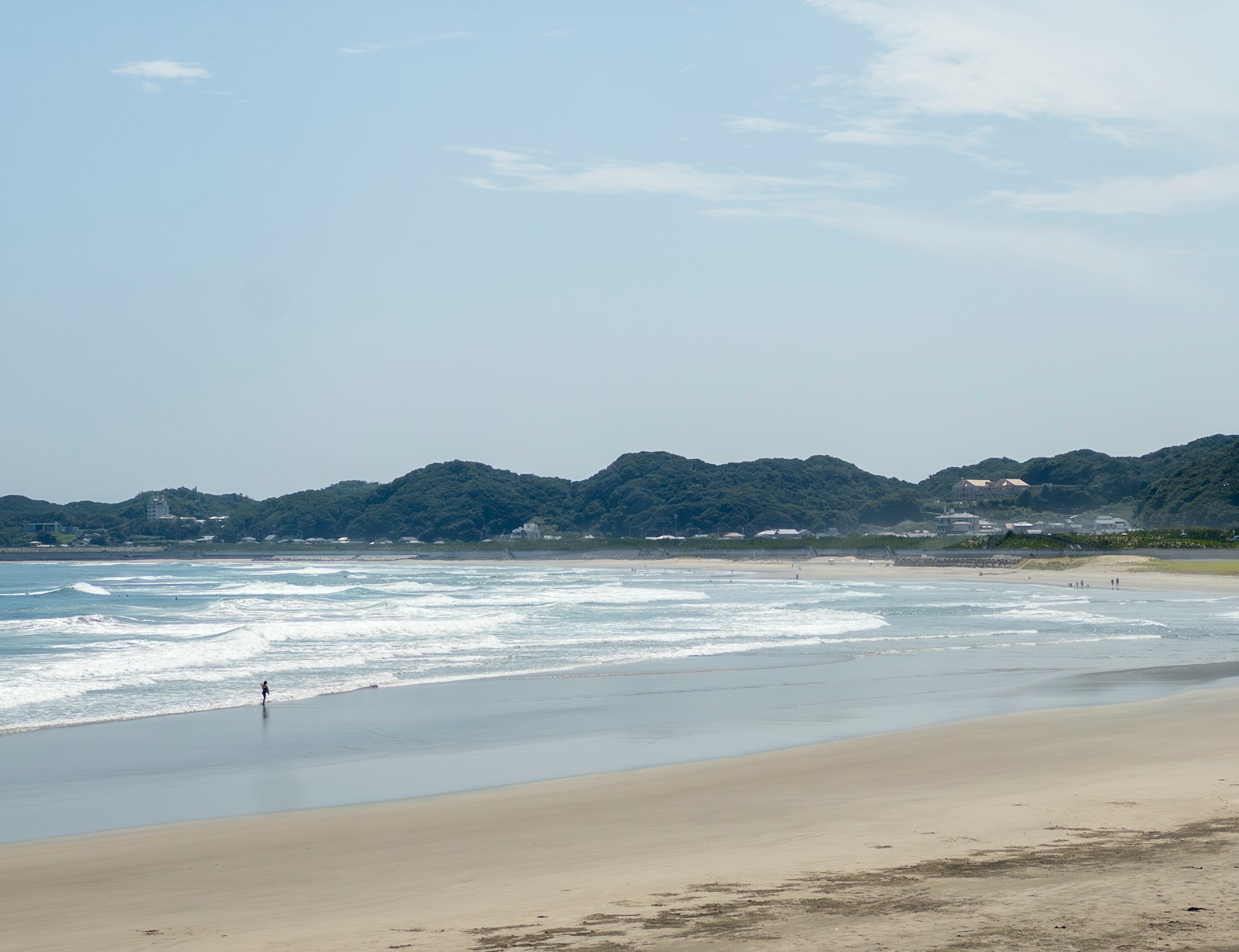 Scenic view of a beach with blue waves and distant hills in the background