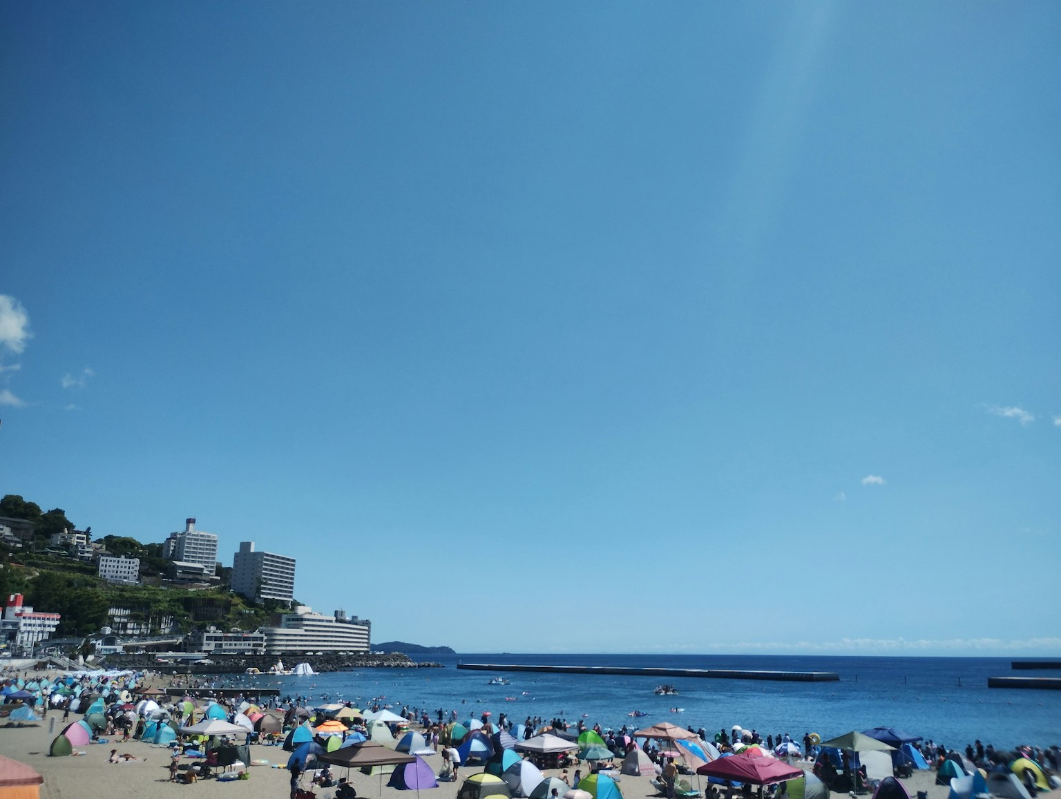 Scène de plage avec des parasols colorés et des gens sous un ciel bleu
